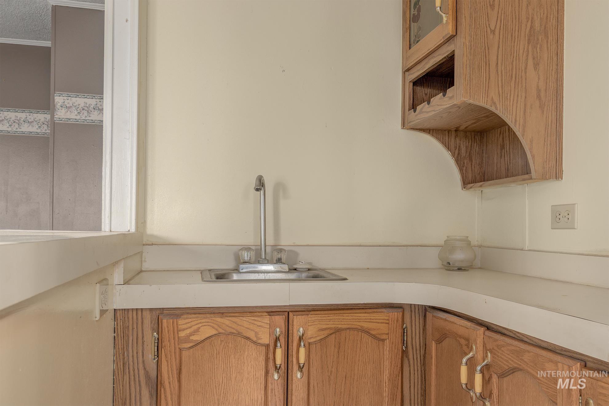 Kitchen featuring open shelves, glass insert cabinets, light countertops, brown cabinets, and a textured ceiling