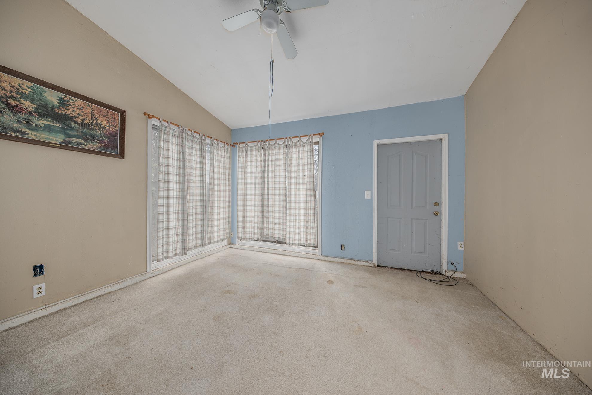 Unfurnished dining area featuring vaulted ceiling, a ceiling fan, and carpet floors