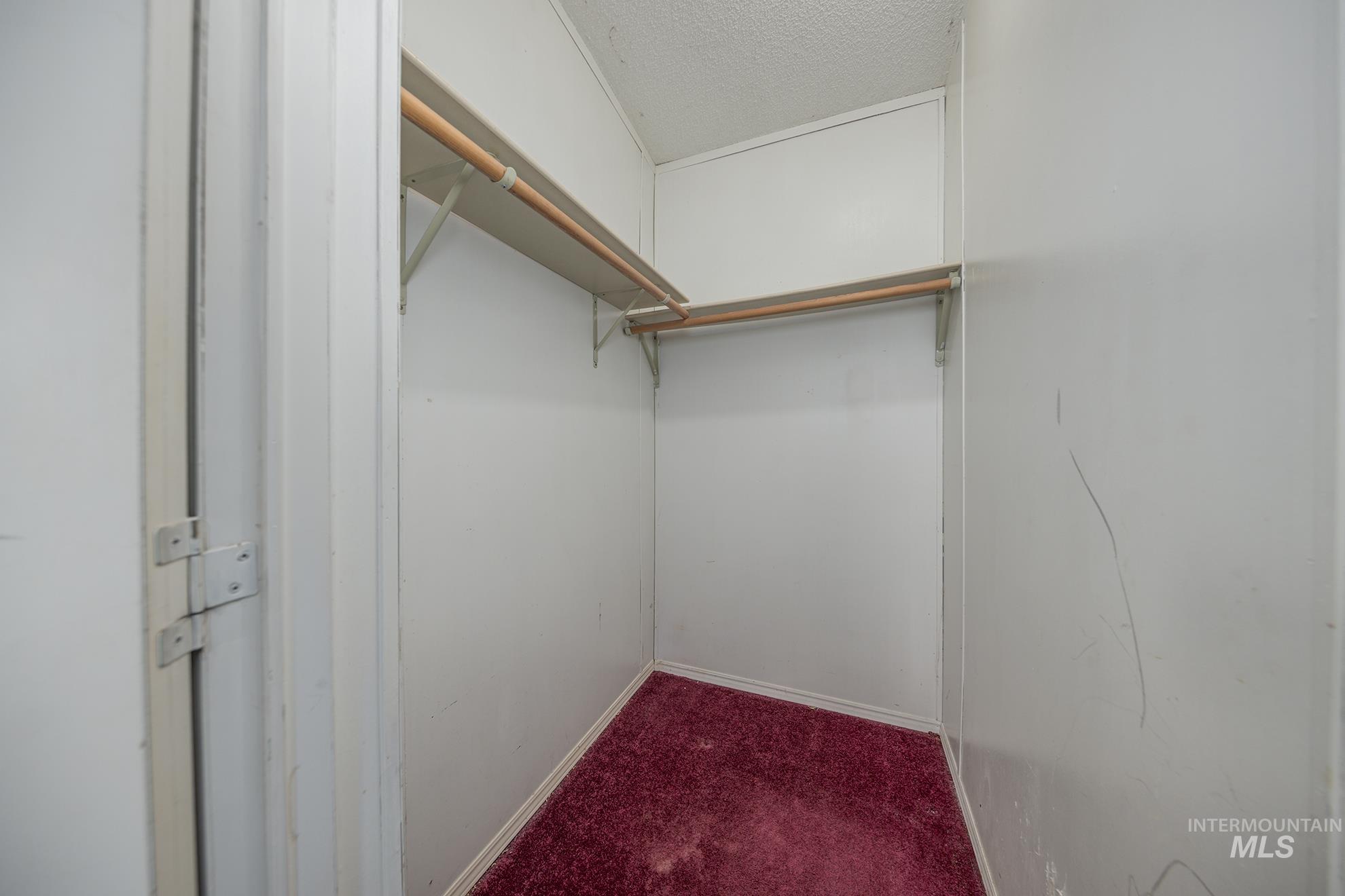 Walk in closet featuring dark colored carpet