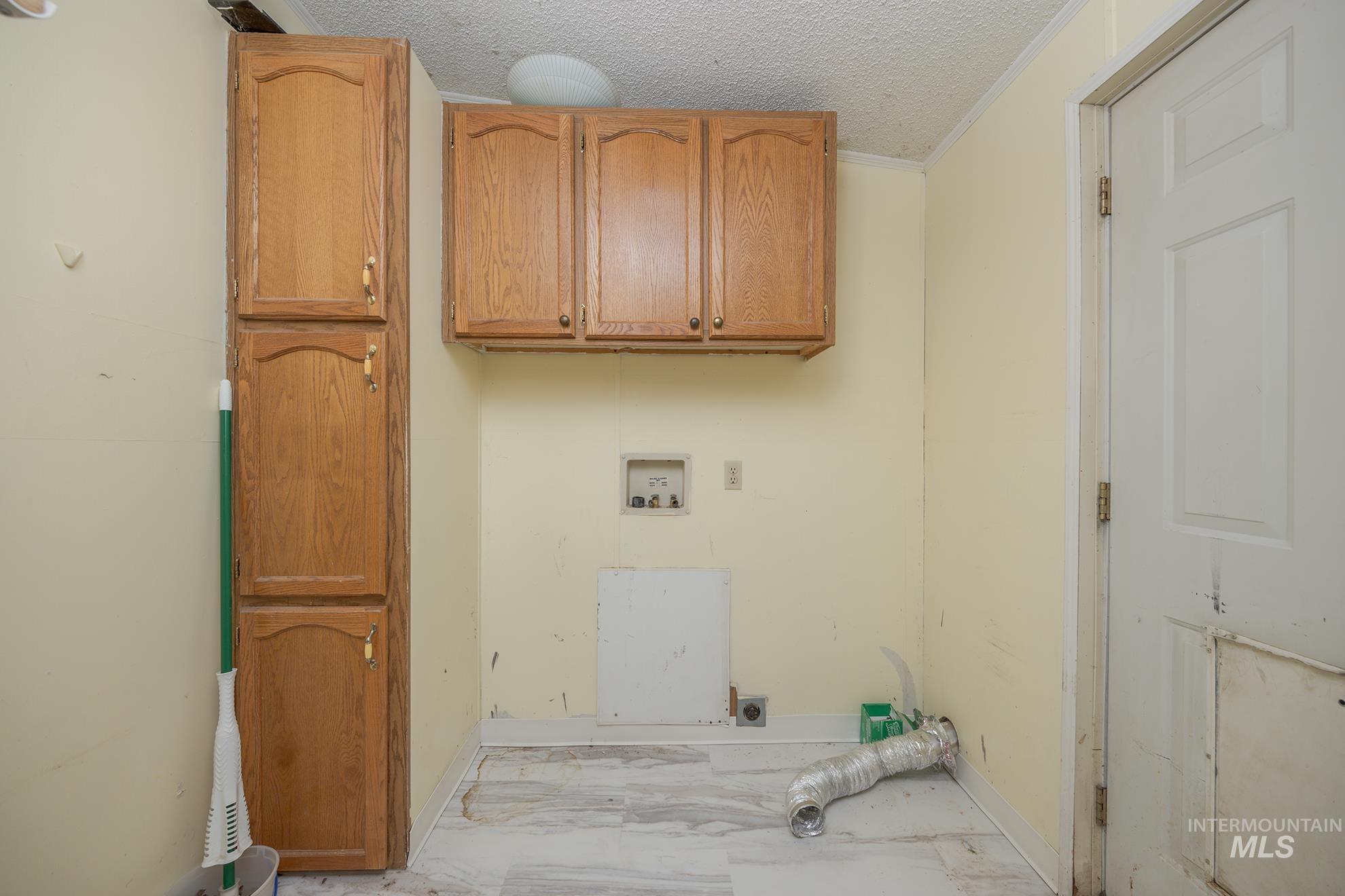 Laundry area with cabinet space, ornamental molding, a textured ceiling, hookup for an electric dryer, and hookup for a washing machine