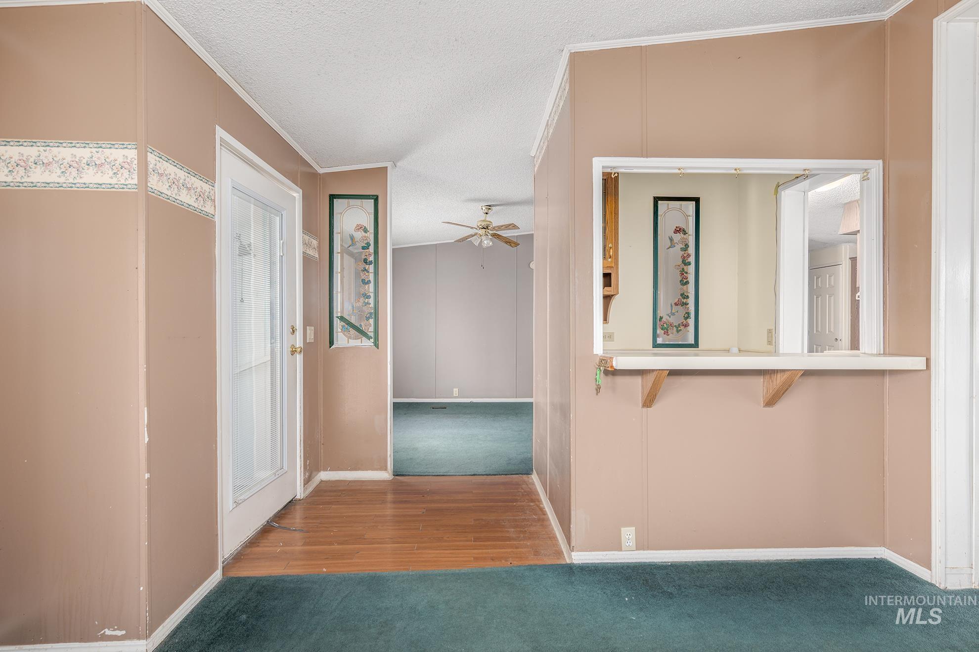 Hallway with crown molding, carpet floors, wood finished floors, and a textured ceiling