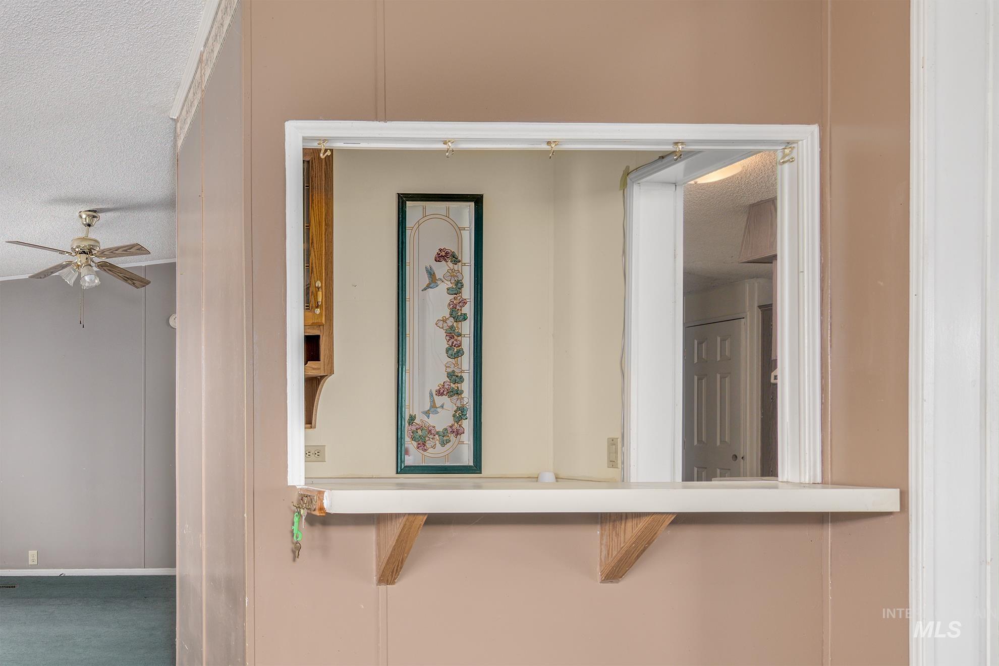 Detailed view of a textured ceiling, carpet flooring, and ceiling fan