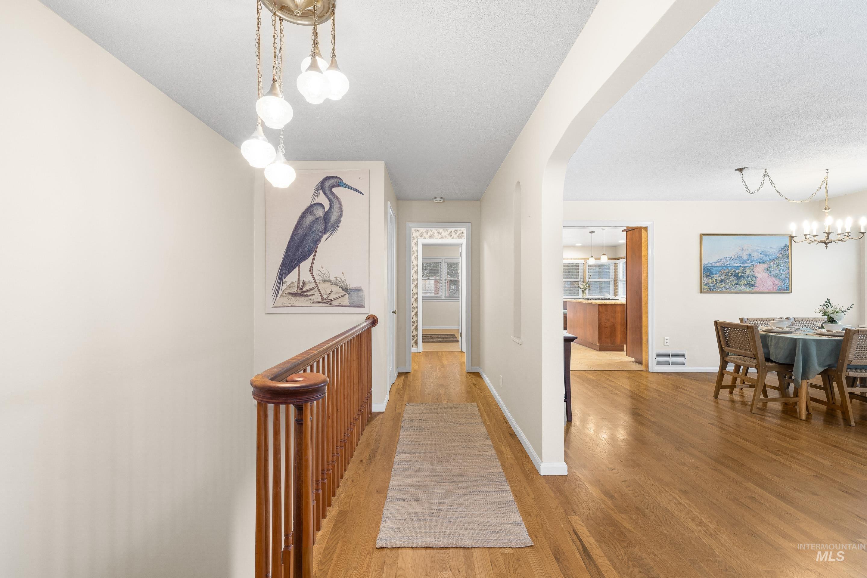 Hallway featuring a chandelier, arched walkways, and light wood-style flooring