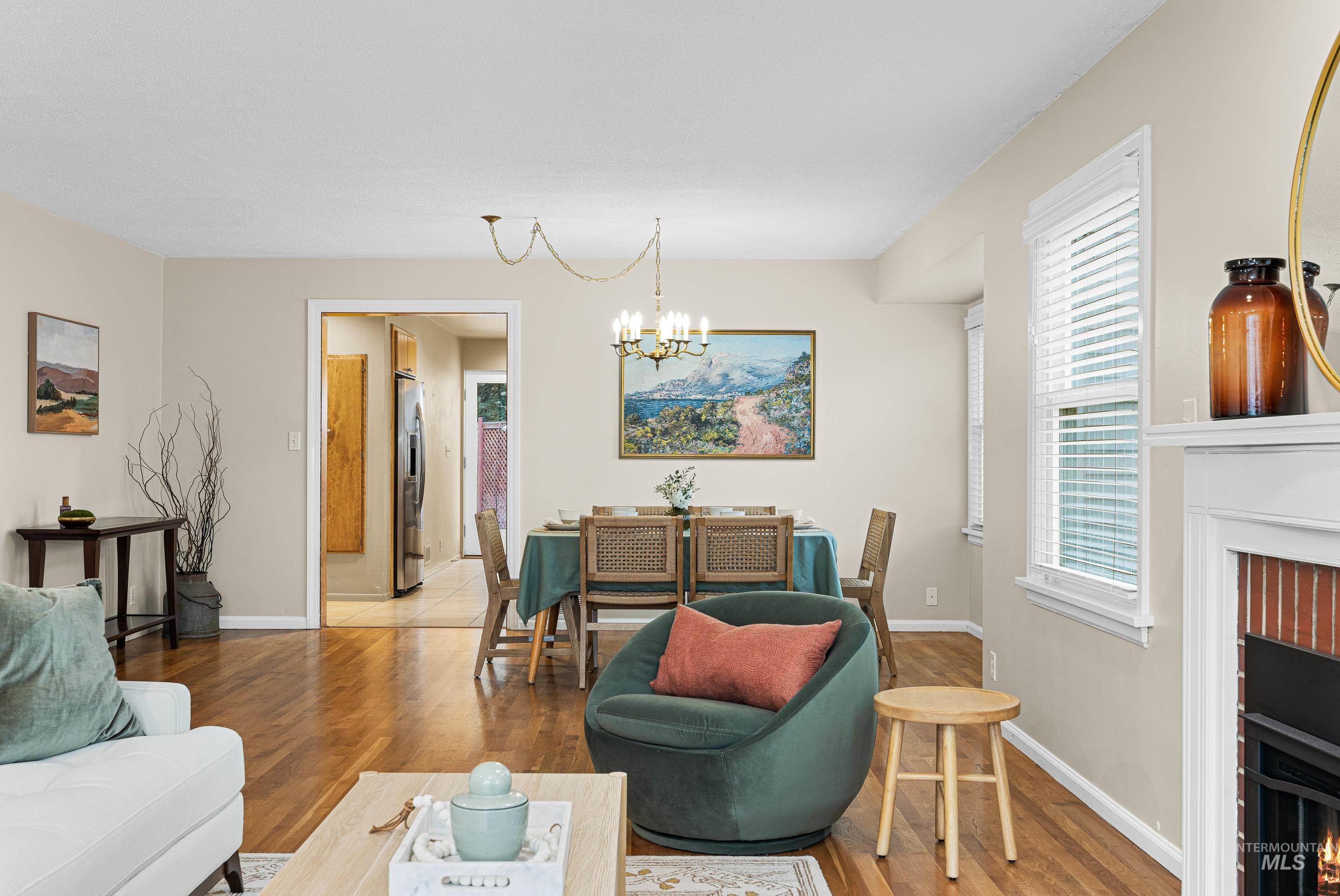 Living room featuring a warm lit fireplace, a chandelier, and wood finished floors