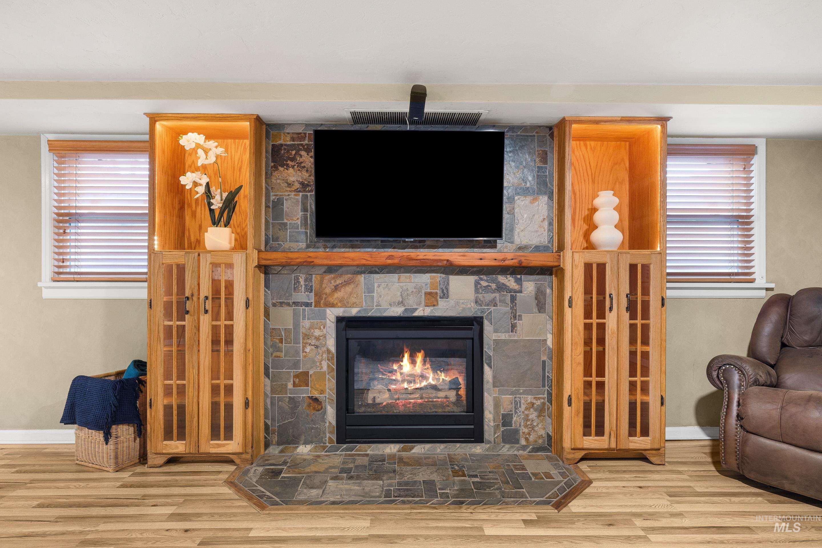 Living area with healthy amount of natural light, a stone fireplace, and wood finished floors