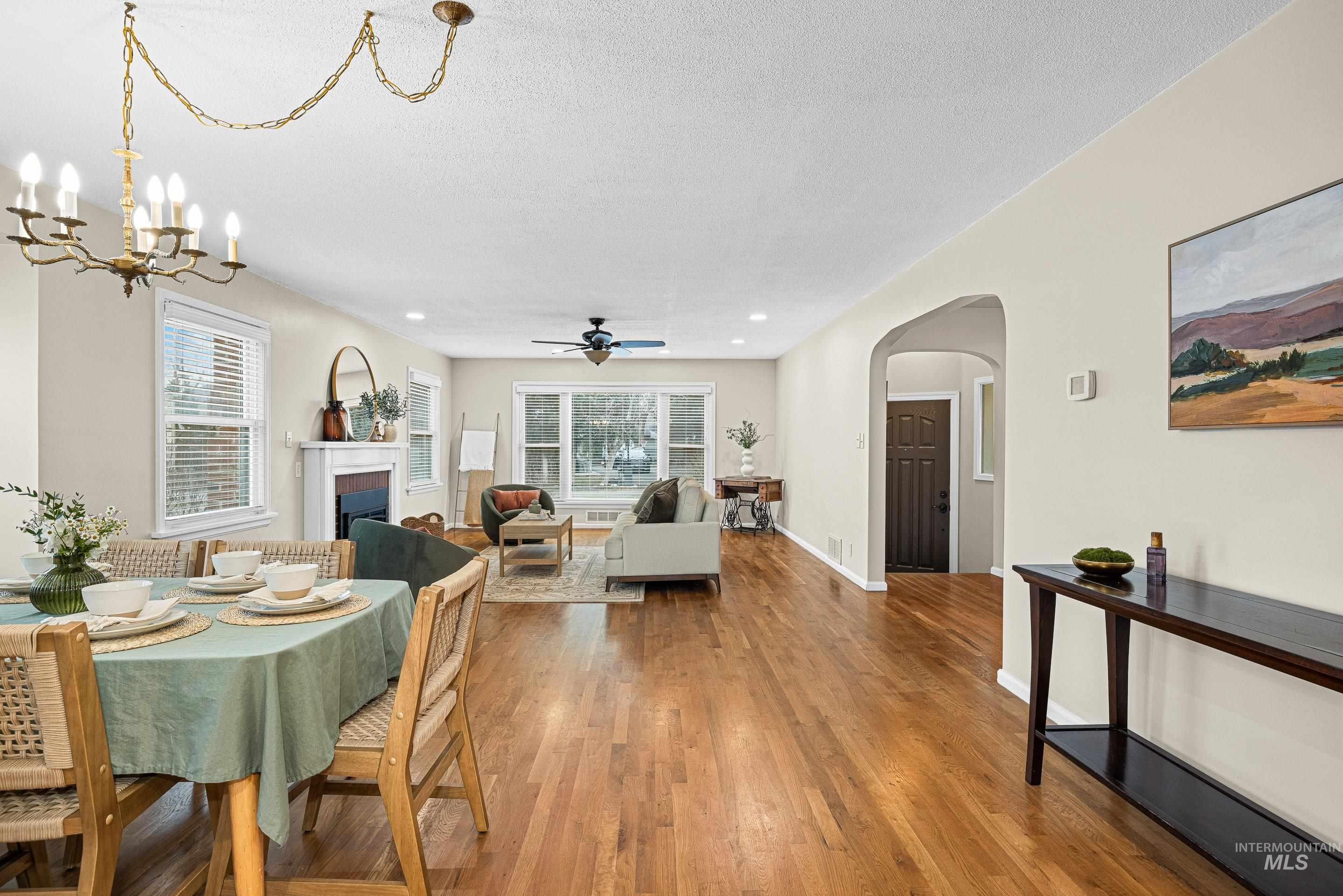 Dining space featuring a fireplace, arched walkways, plenty of natural light, wood-type flooring, and a textured ceiling