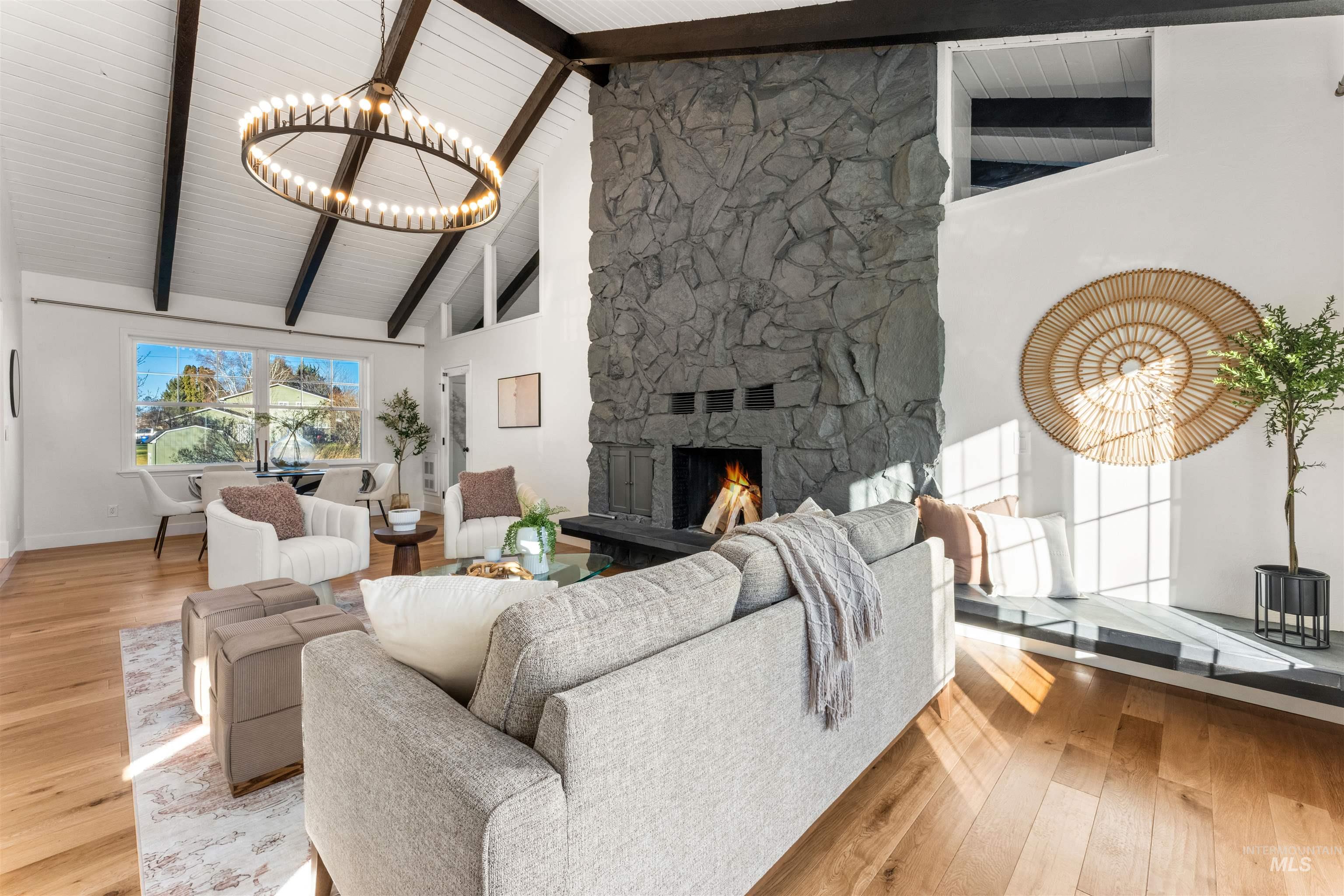 Living area with high vaulted ceiling, beamed ceiling, a fireplace, light wood finished floors, and a chandelier