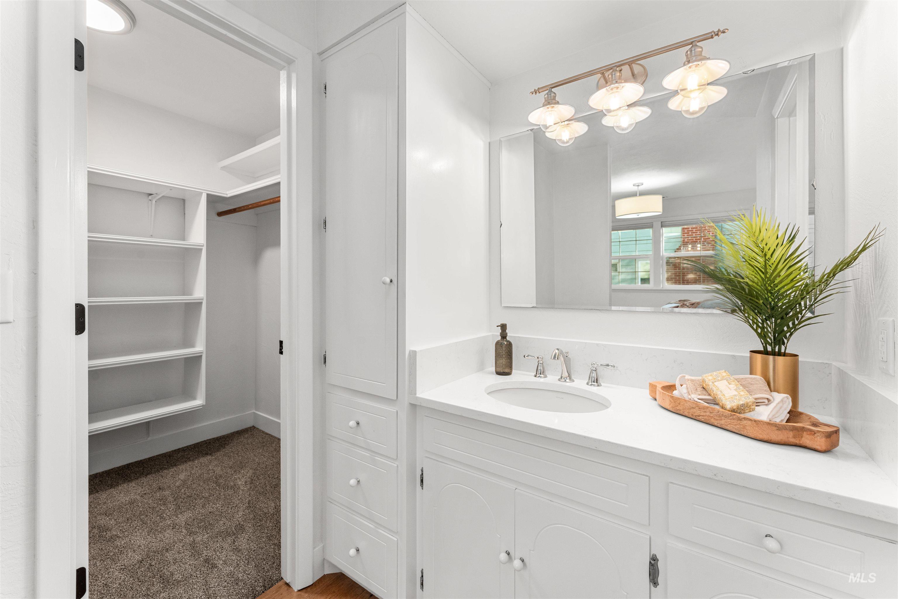 Full bathroom with vanity, dark carpet, and a walk in closet