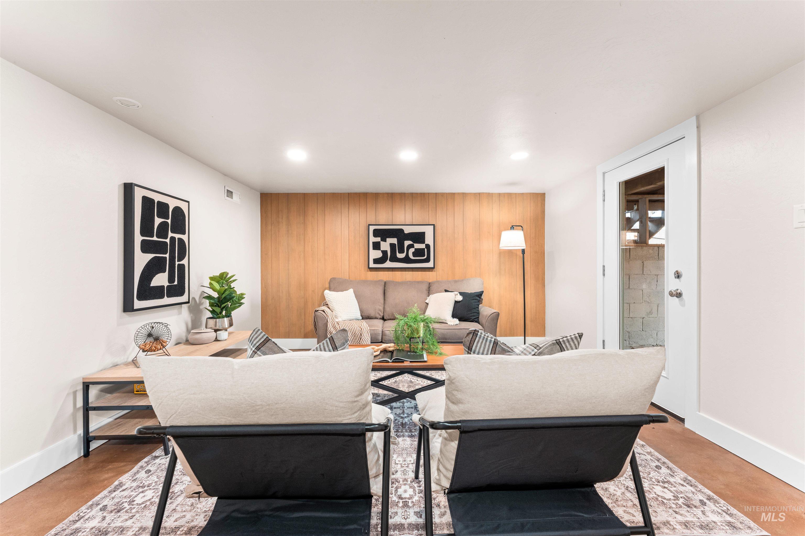 Living area with an accent wall, wooden walls, concrete floors, and recessed lighting