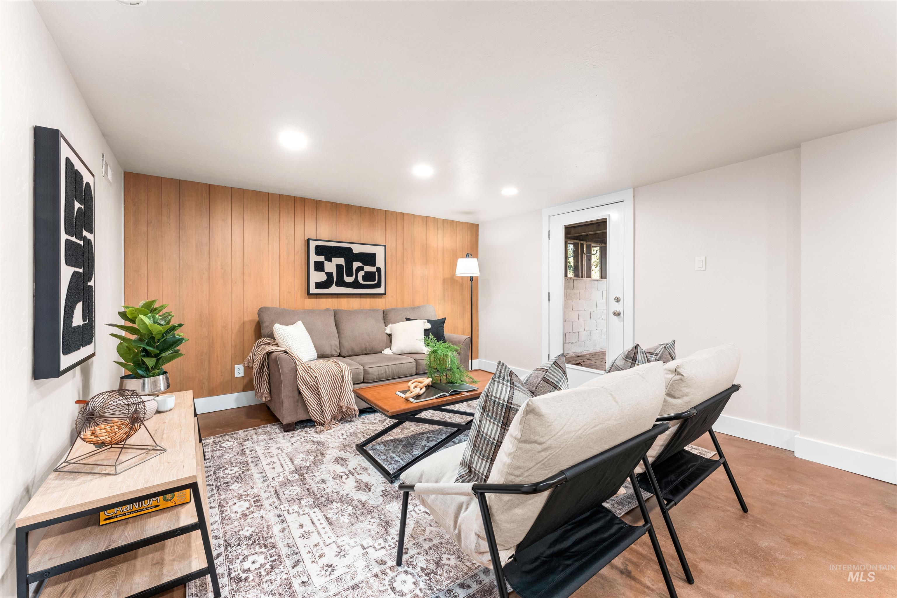 Living room featuring wooden walls, recessed lighting, an accent wall, and concrete flooring