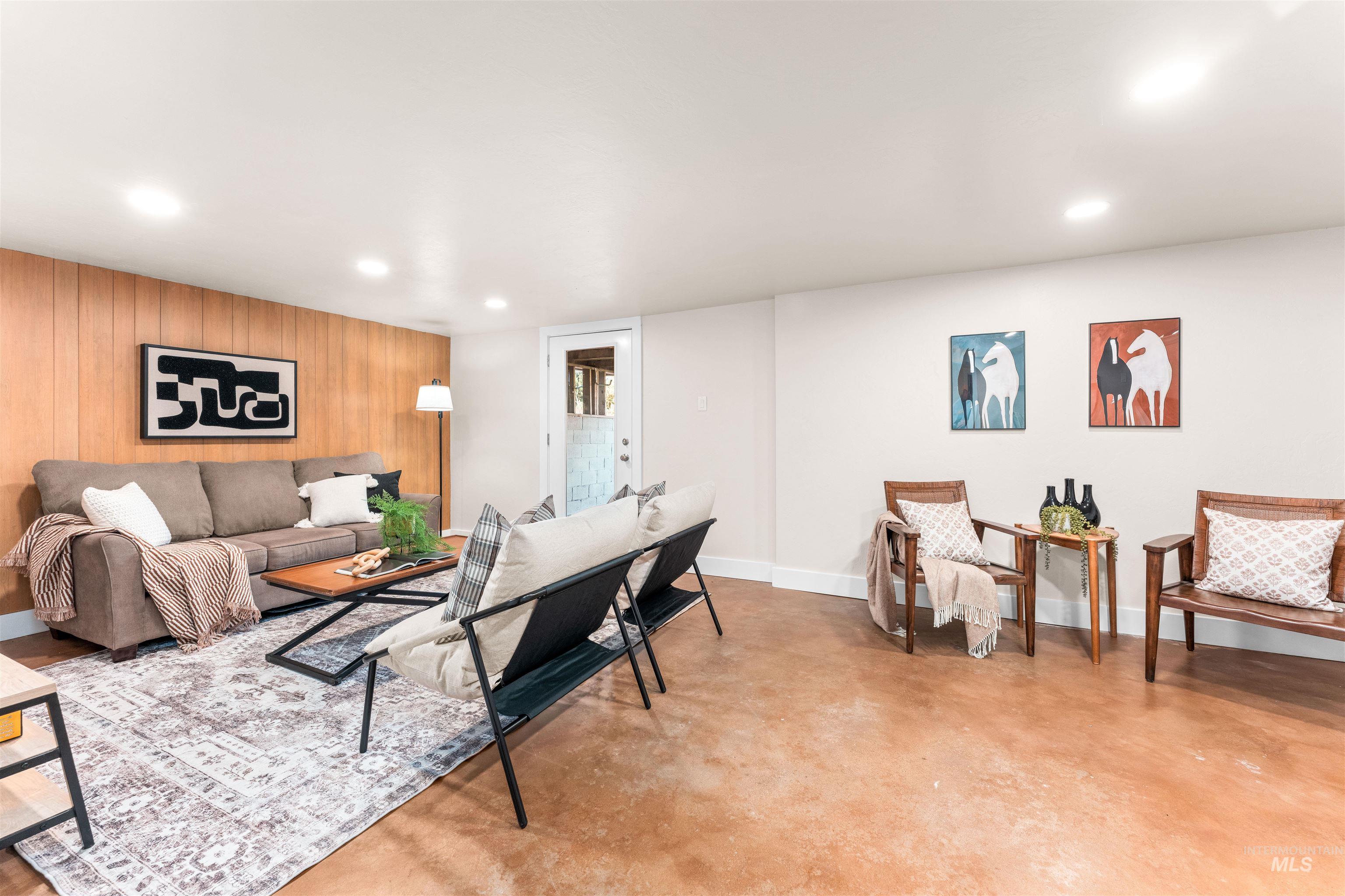 Living area with concrete flooring, wooden walls, an accent wall, and recessed lighting