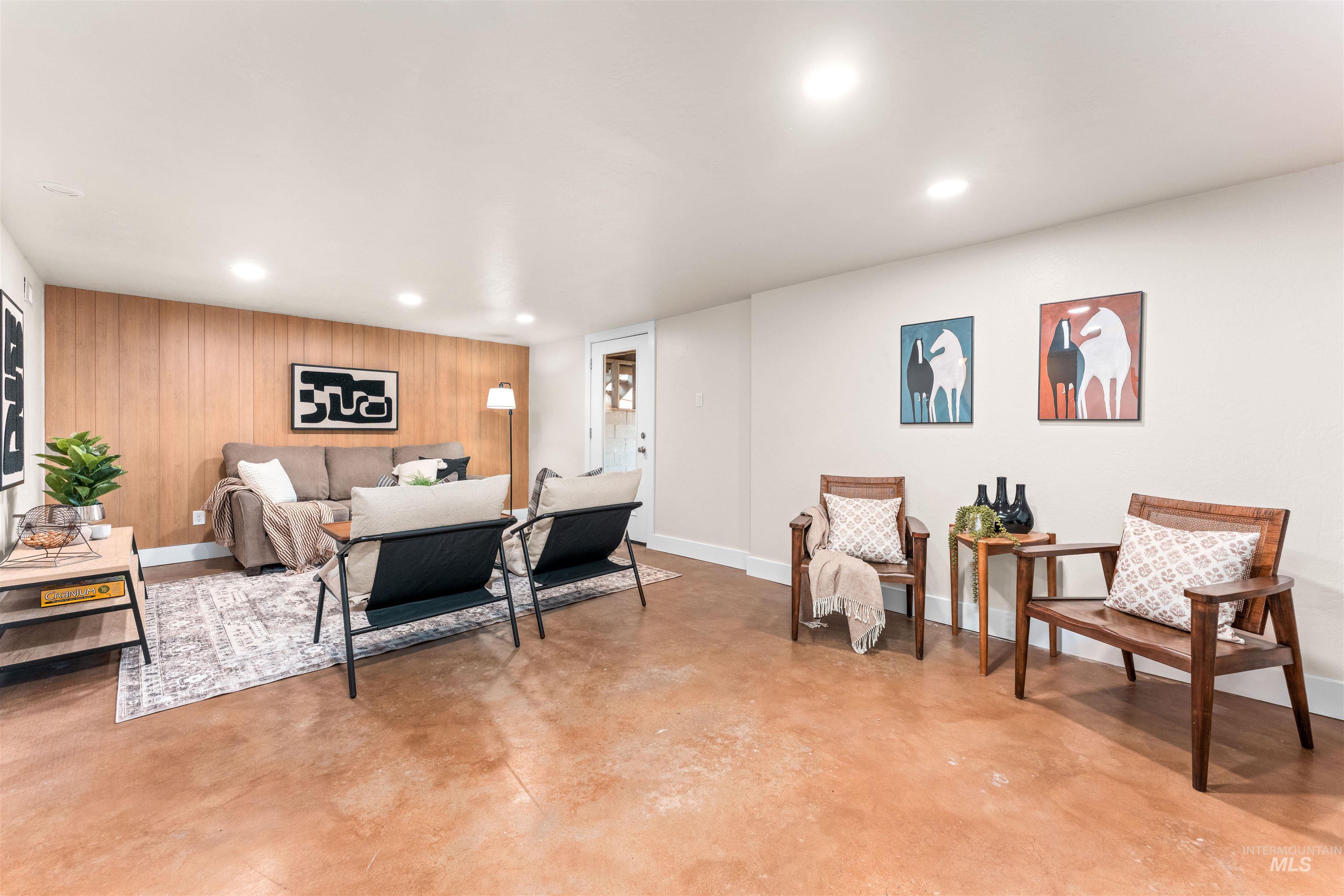 Living area with concrete flooring, wood walls, recessed lighting, and an accent wall