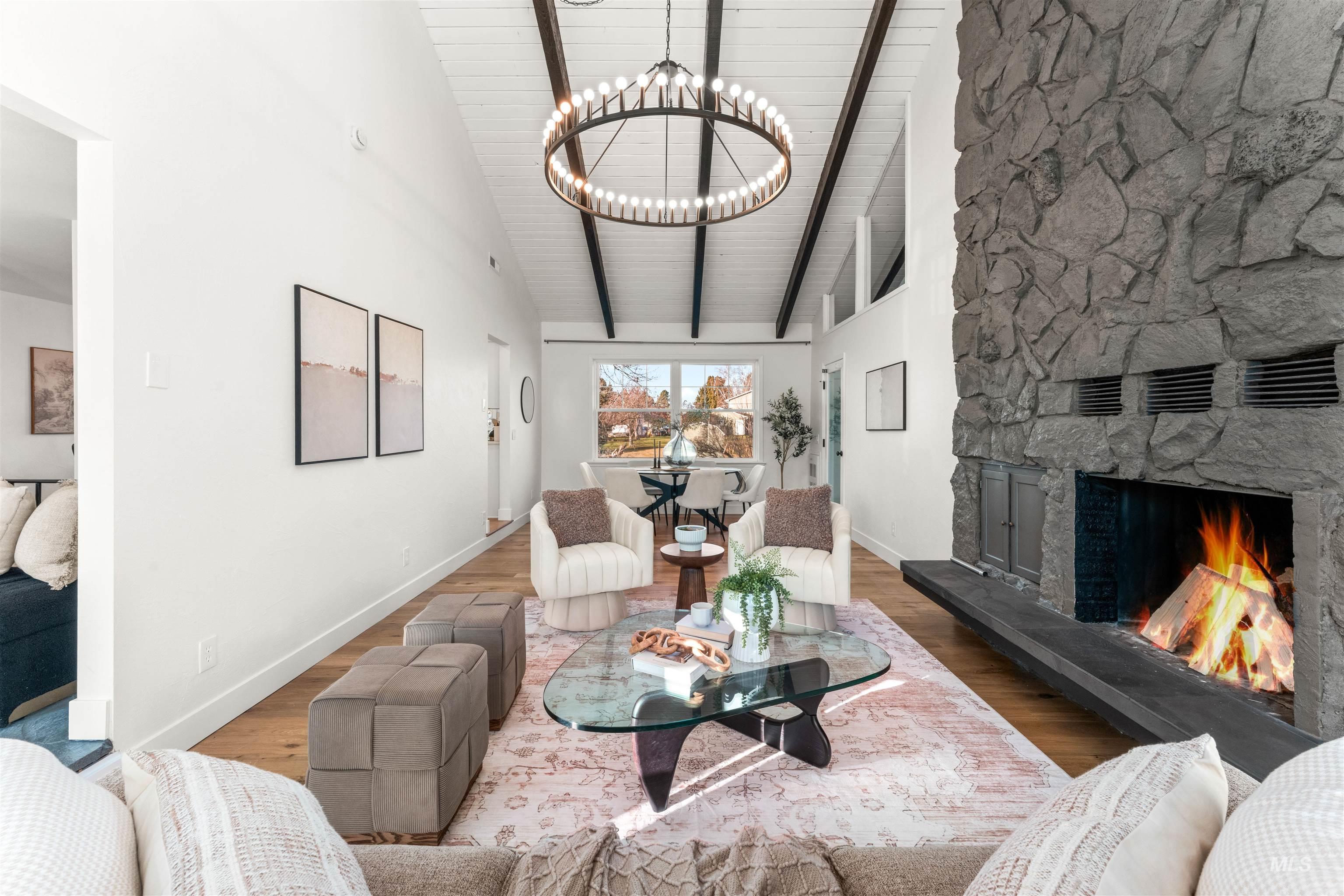 Living room featuring high vaulted ceiling, a fireplace, wood finished floors, a chandelier, and a wooden ceiling with exposed beams