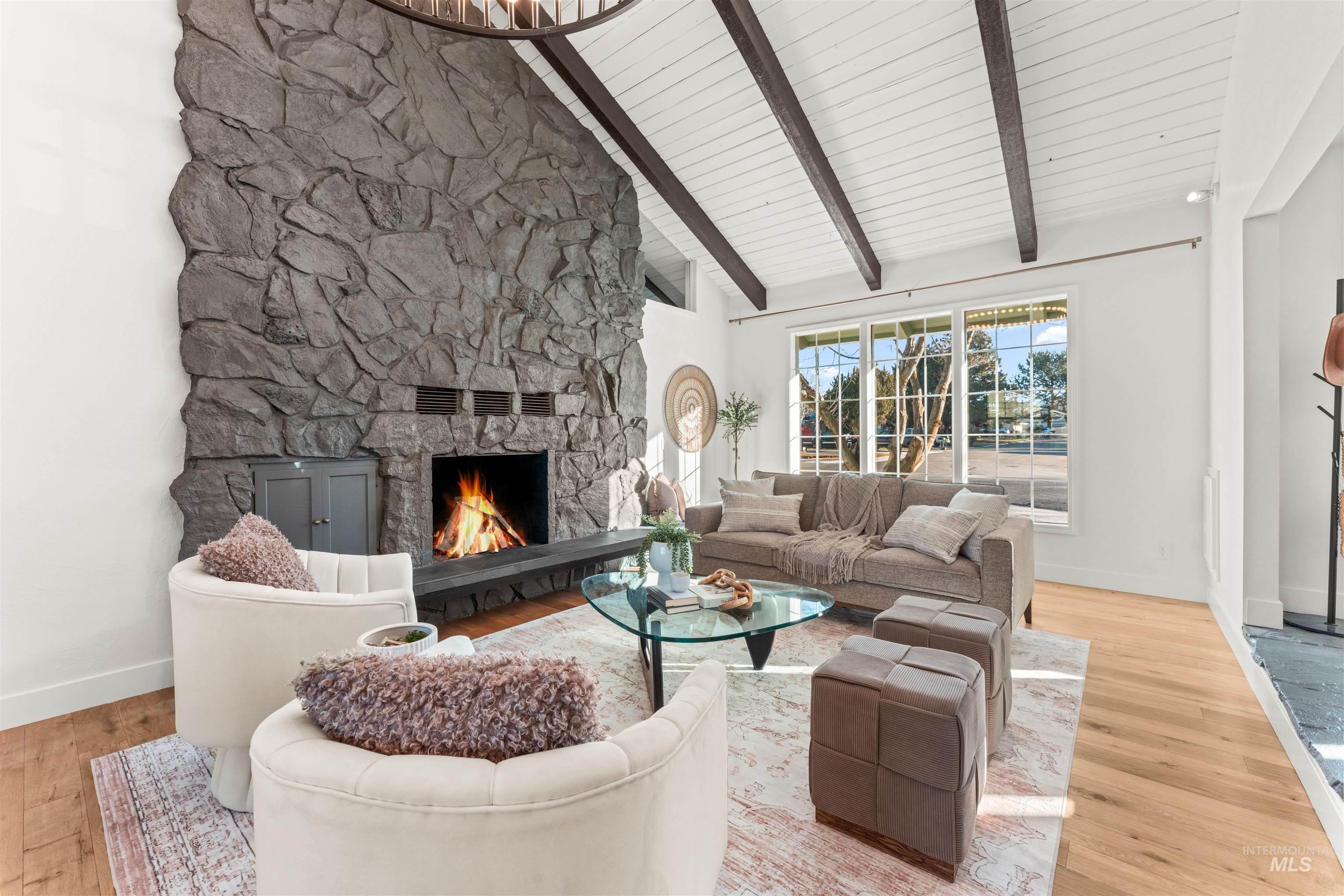 Living area featuring a fireplace, beamed ceiling, high vaulted ceiling, and light wood-type flooring