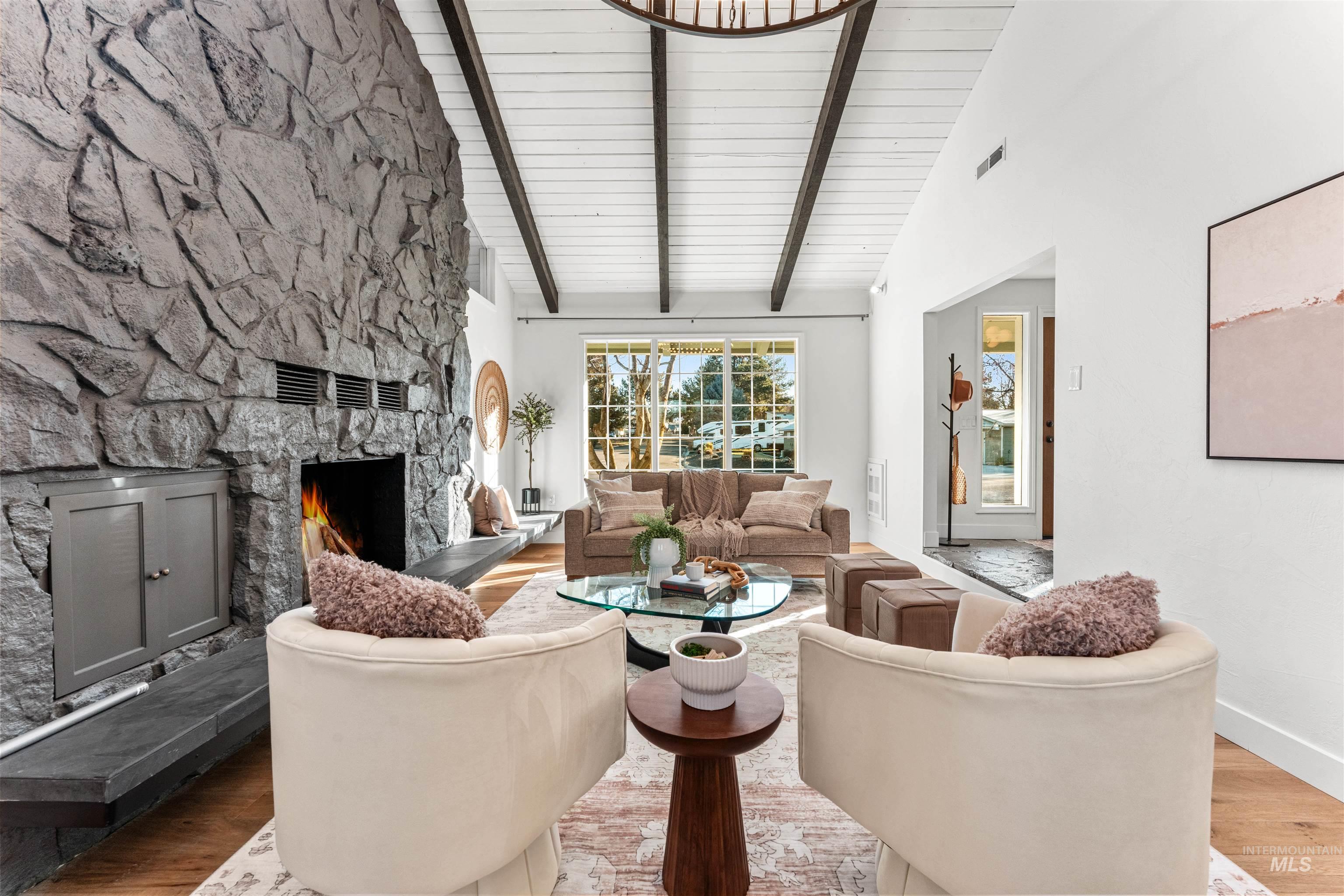 Living room featuring a fireplace, wood finished floors, high vaulted ceiling, and beamed ceiling