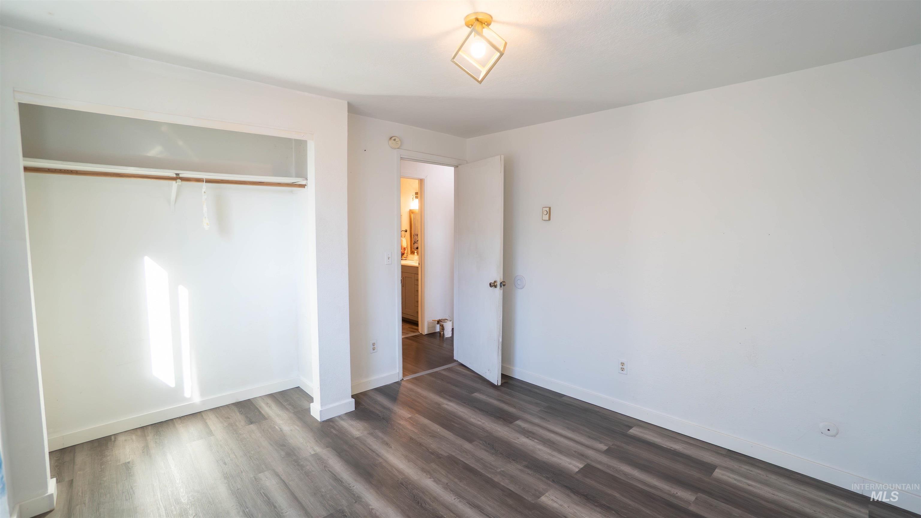Unfurnished bedroom featuring a closet and dark wood-type flooring