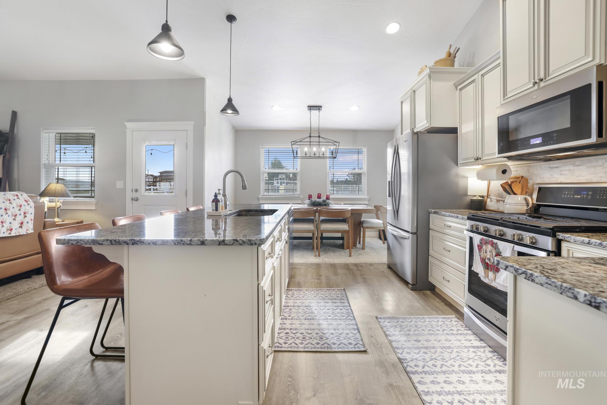 Kitchen featuring appliances with stainless steel finishes, a breakfast bar area, decorative light fixtures, dark stone countertops, and recessed lighting