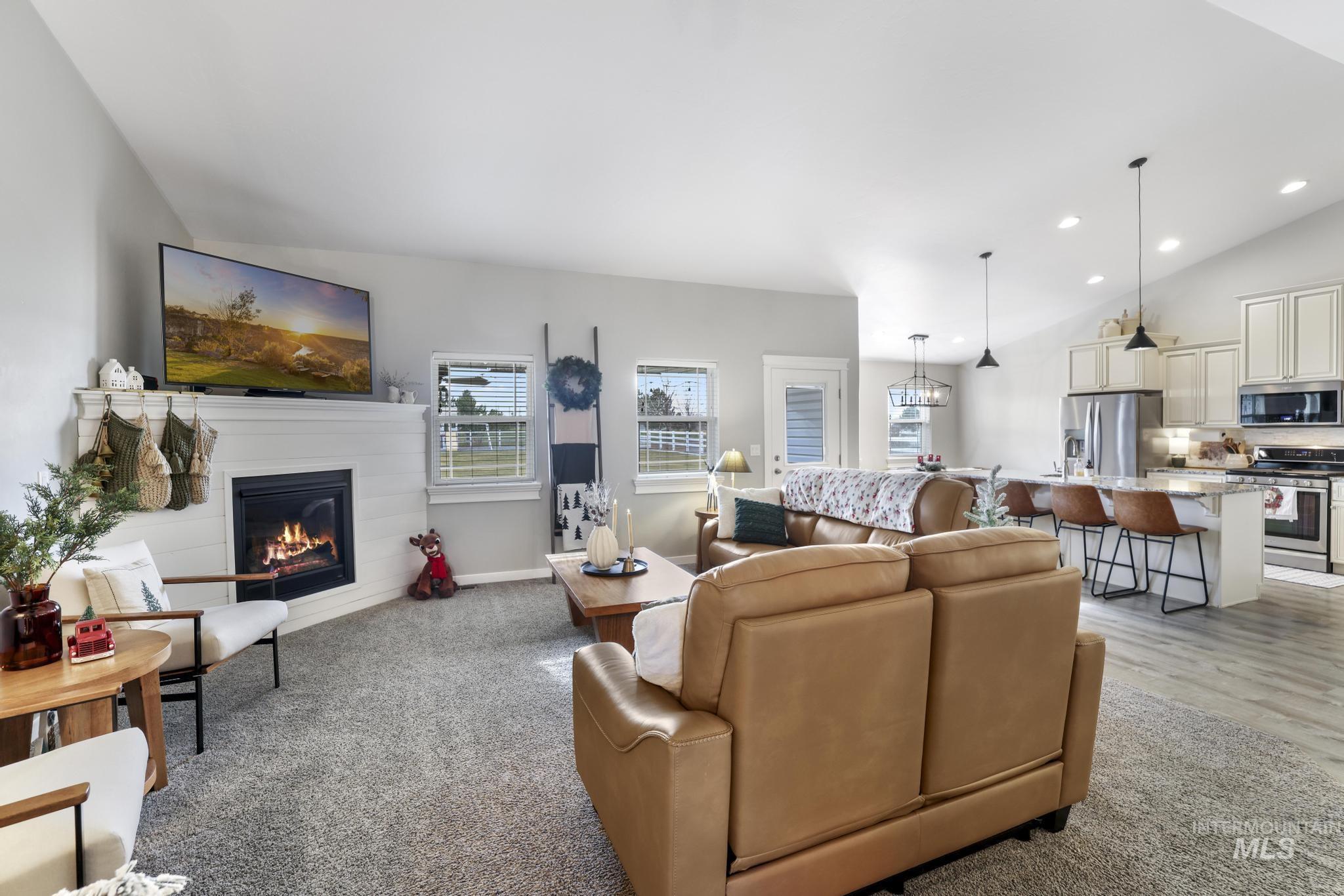 Living area with lofted ceiling, a glass covered fireplace, recessed lighting, and light colored carpet