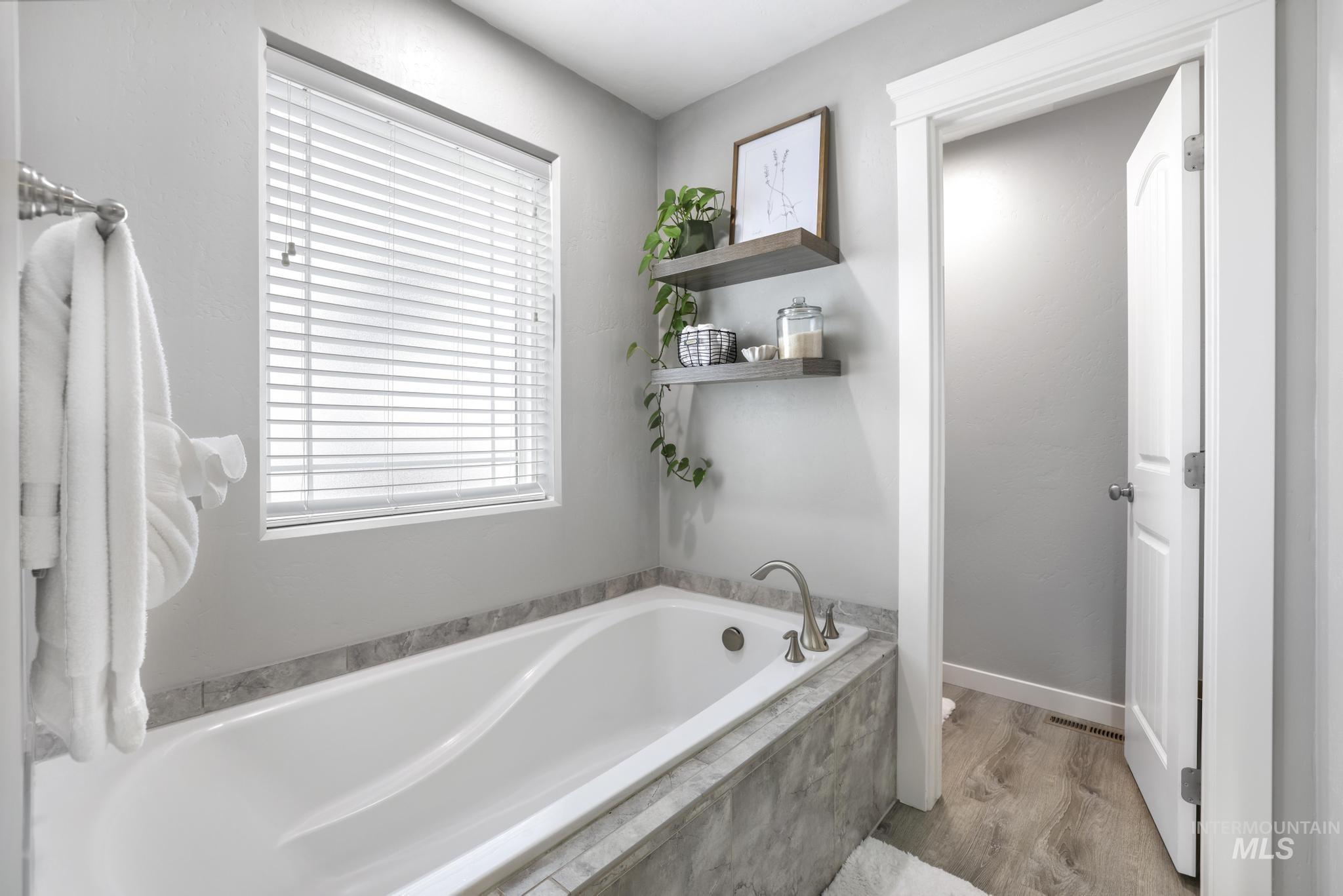 Bathroom featuring a garden tub and light wood-style flooring