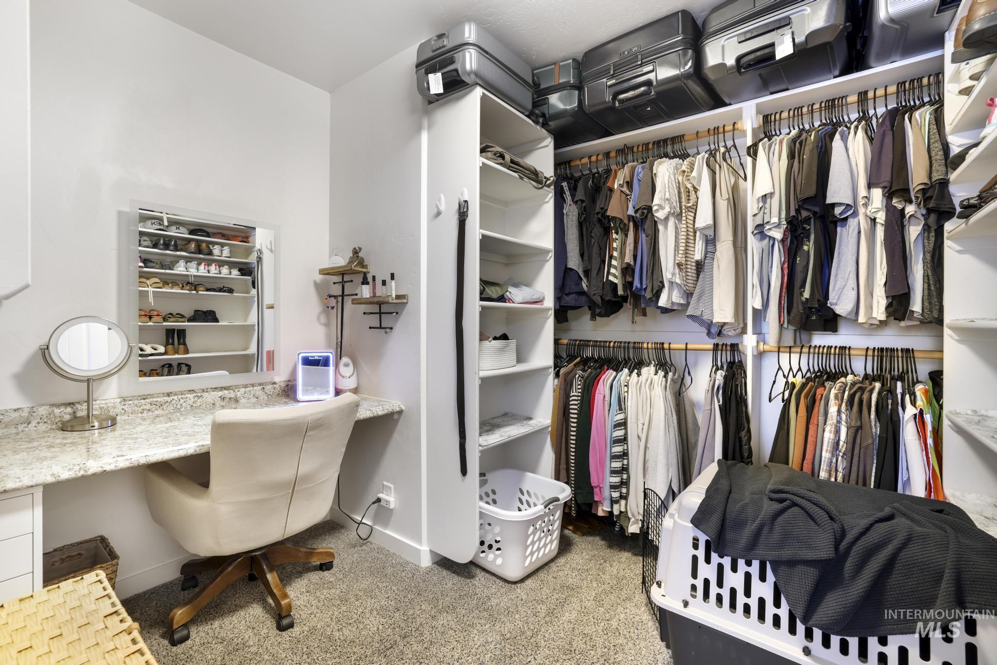 Walk in closet featuring light colored carpet and built in desk