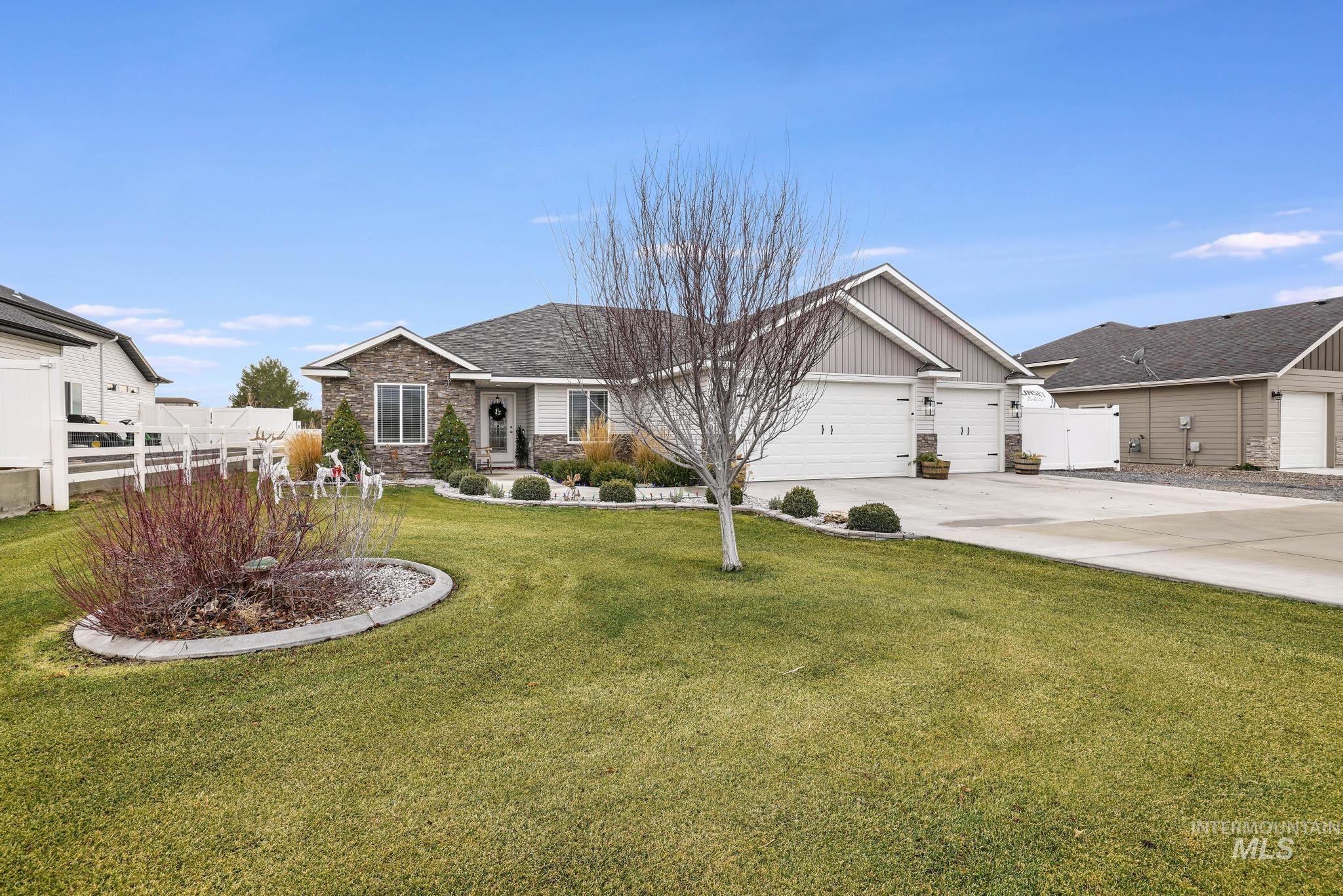 View of front of house with stone siding, driveway, board and batten siding, and an attached garage