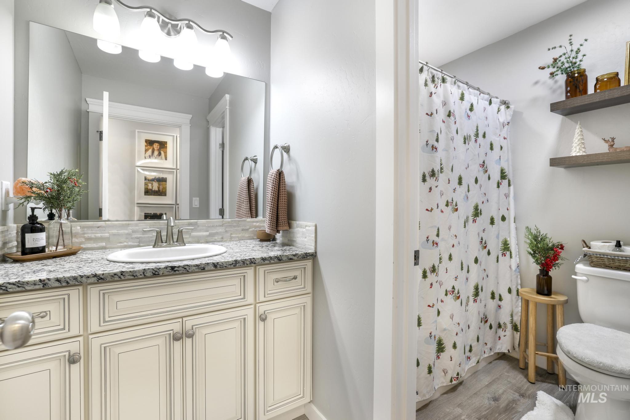 Bathroom featuring a shower with shower curtain, vanity, and light wood finished floors