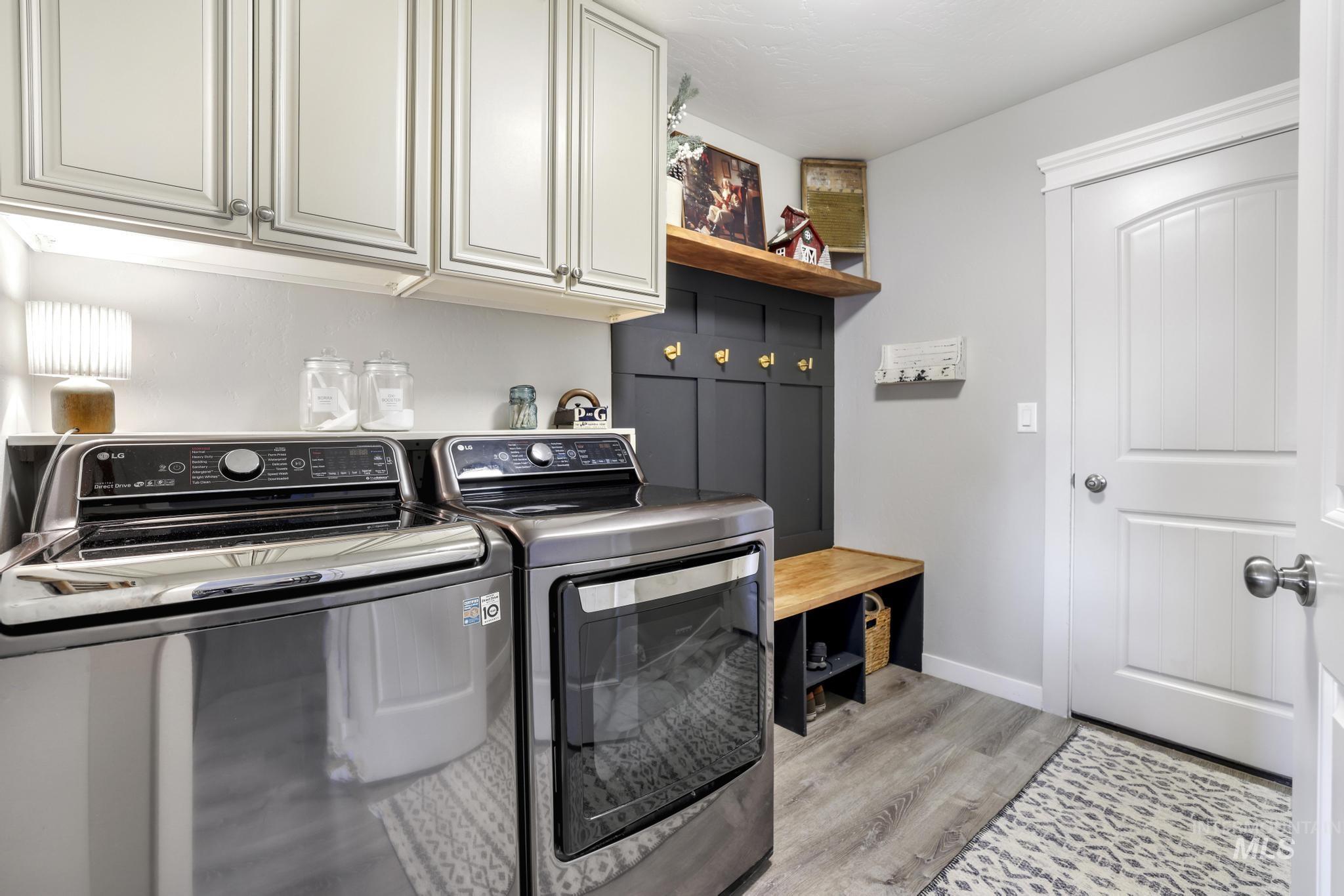Laundry area with light wood-type flooring, separate washer and dryer, and cabinet space