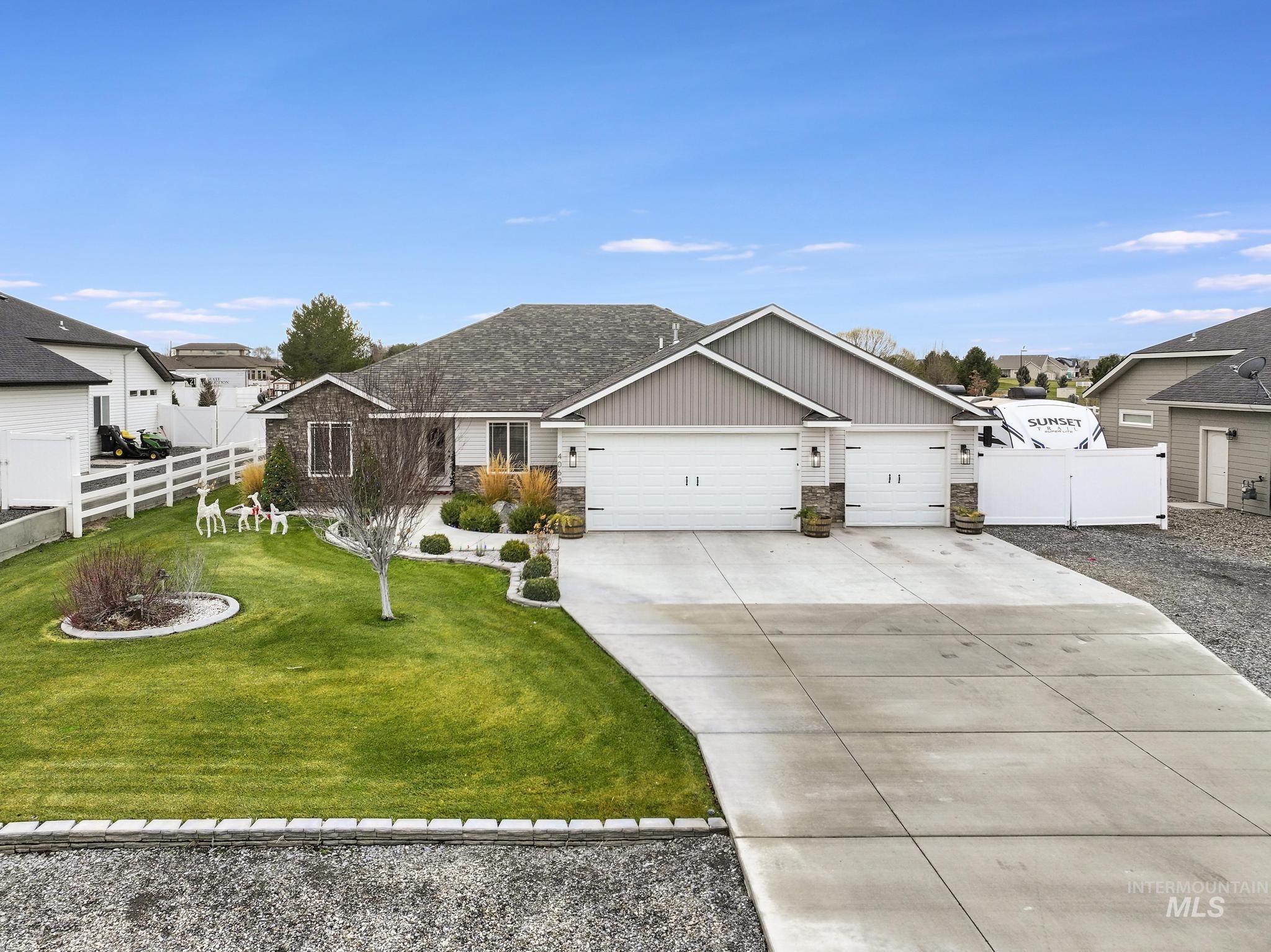 View of front of property featuring stone siding, board and batten siding, driveway, and a garage