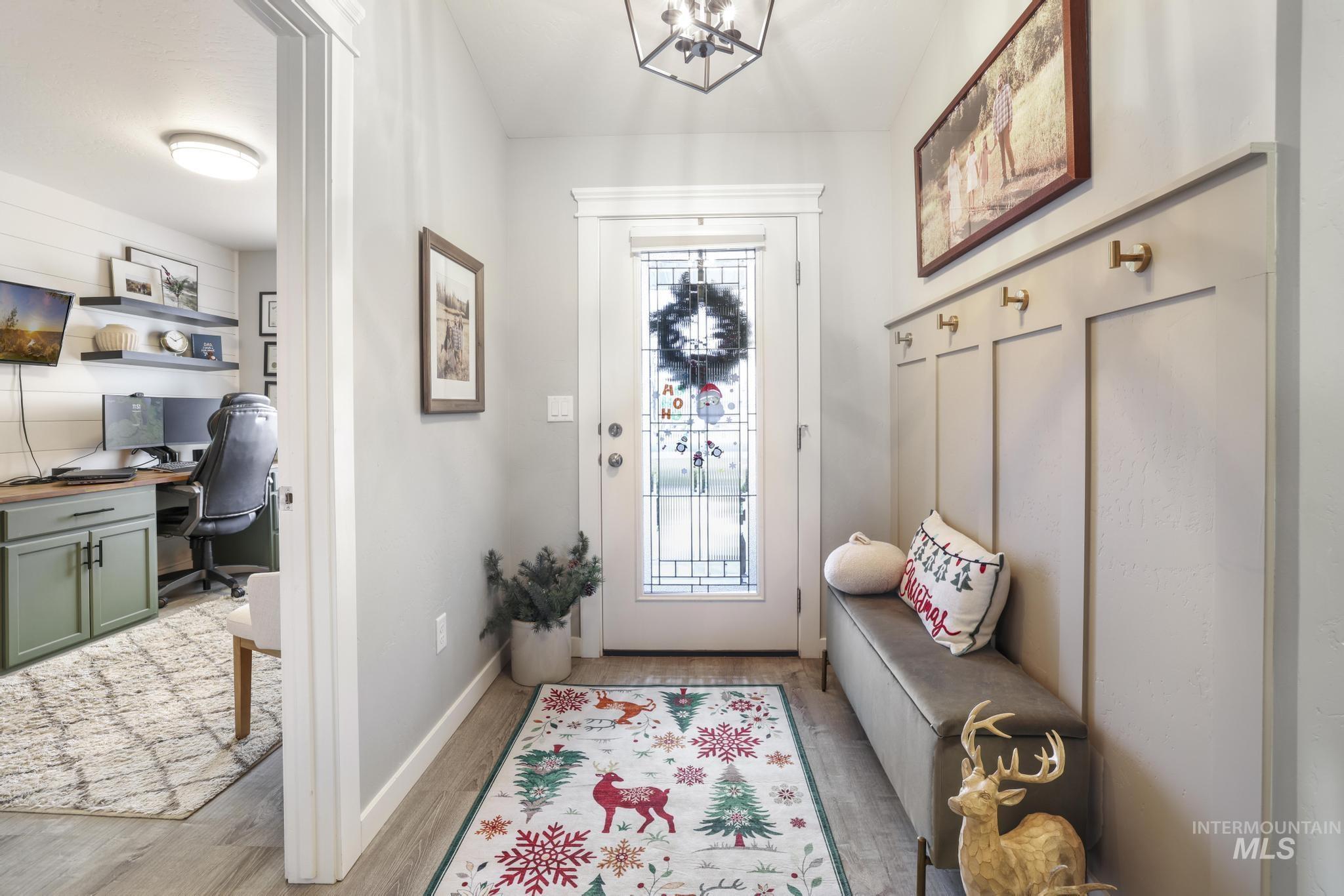 Mudroom featuring light wood finished floors, built in desk, and a chandelier