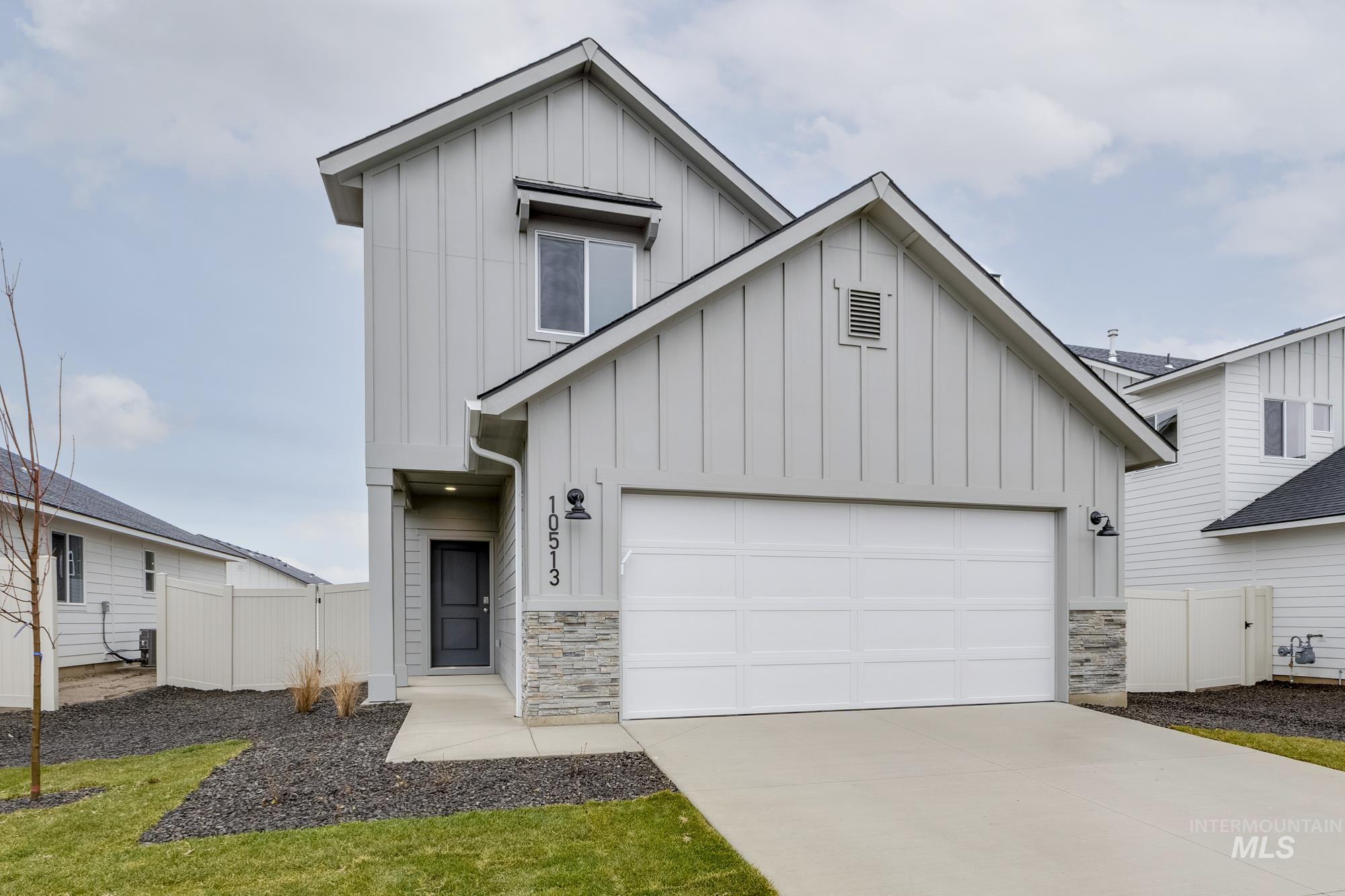 Modern farmhouse featuring board and batten siding, stone siding, driveway, and a garage