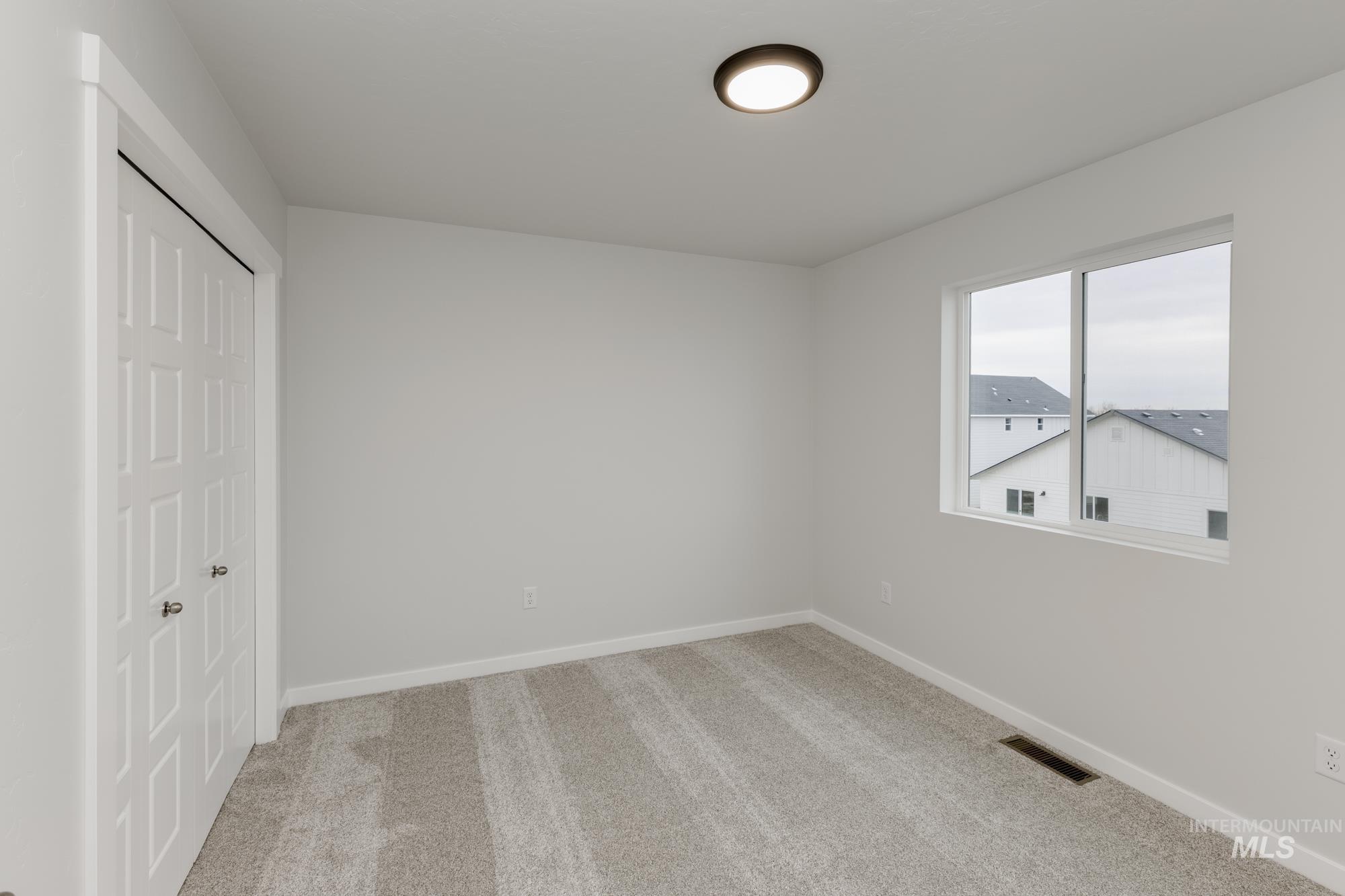 Unfurnished bedroom featuring light carpet and a closet