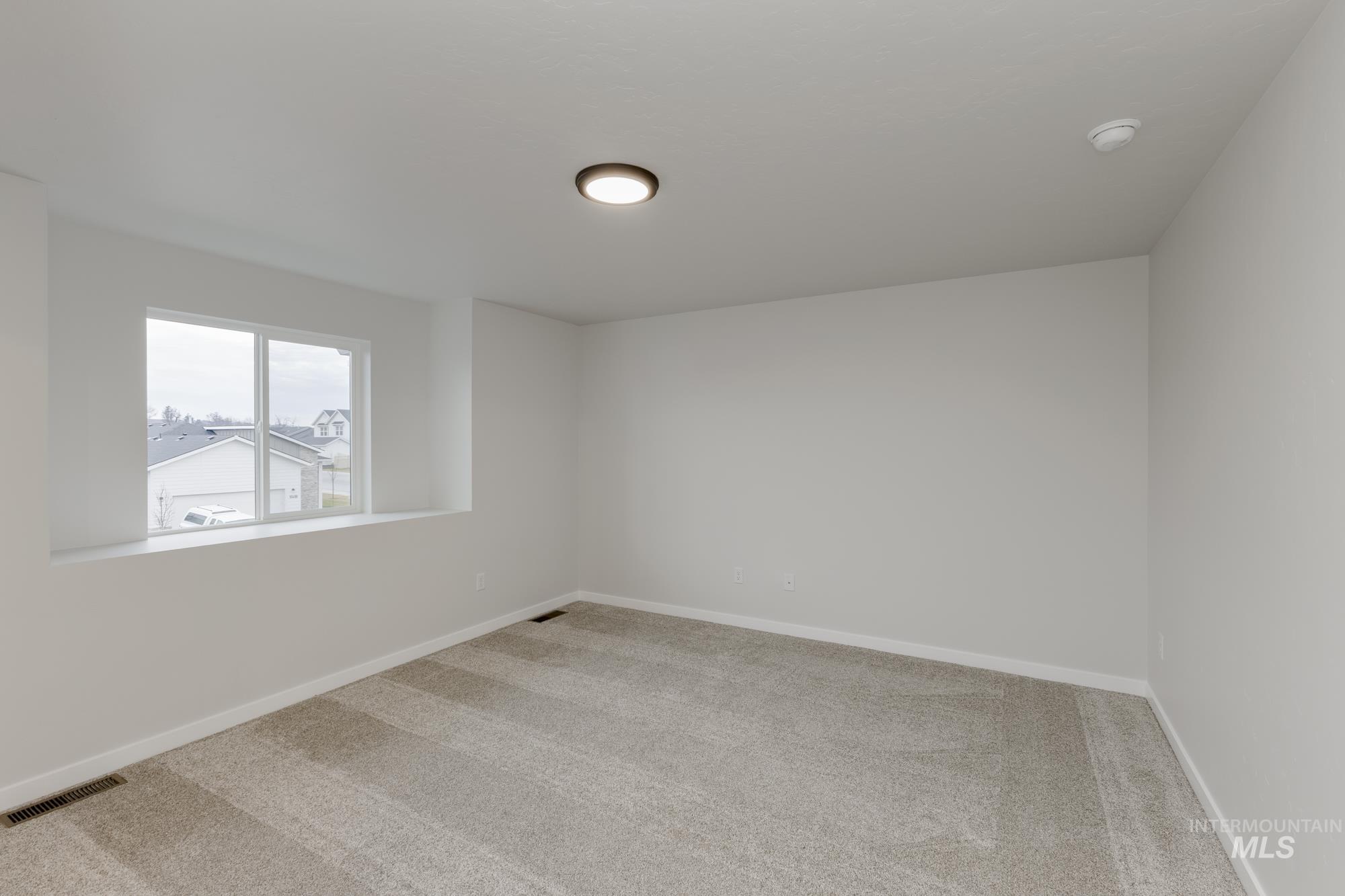 Empty room featuring light colored carpet and baseboards