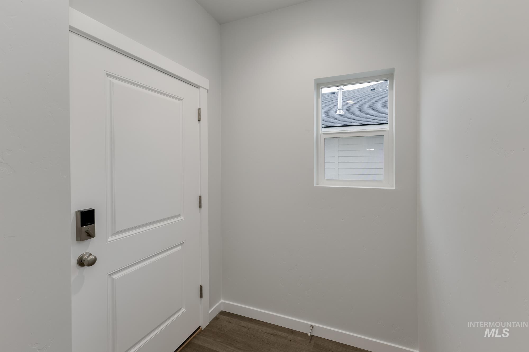 Laundry area with dark wood-type flooring and baseboards