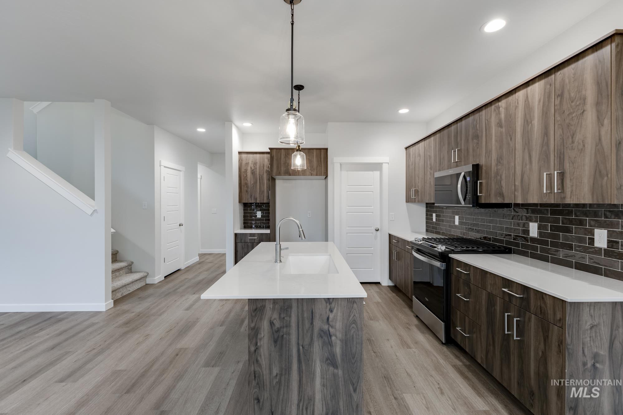 Kitchen with modern cabinets, appliances with stainless steel finishes, decorative backsplash, a kitchen island with sink, and recessed lighting