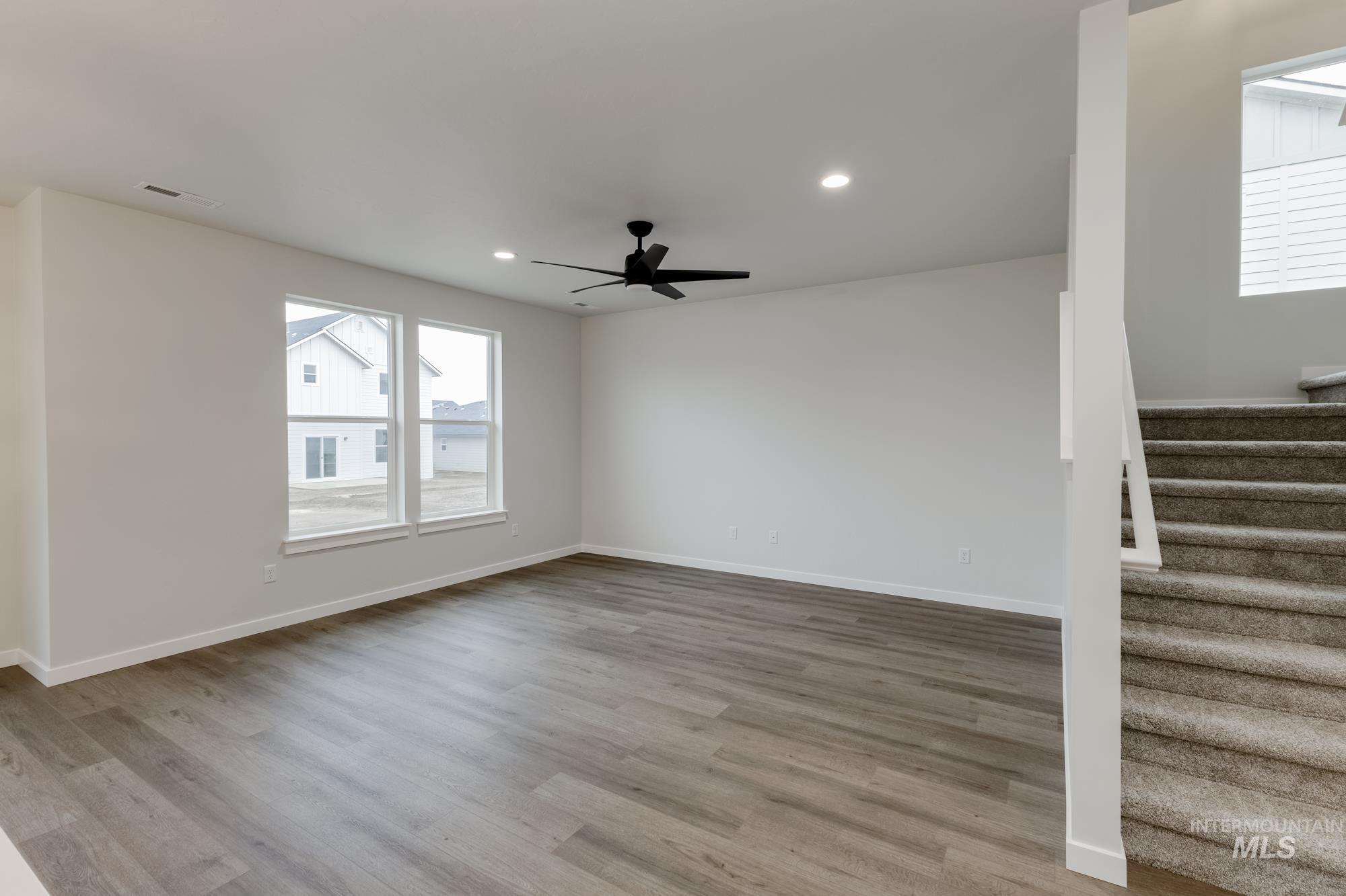 Empty room featuring light wood finished floors, stairs, recessed lighting, and ceiling fan