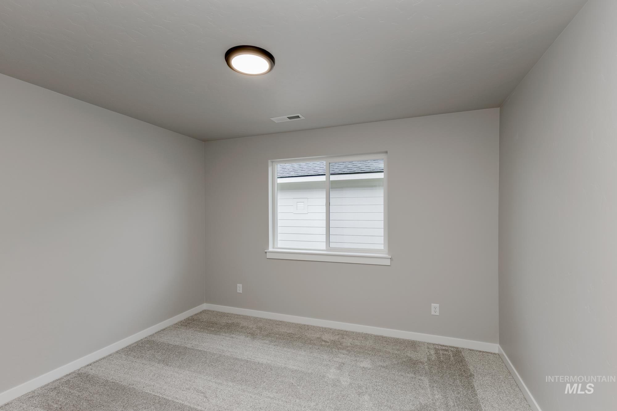 Empty room featuring light colored carpet and baseboards