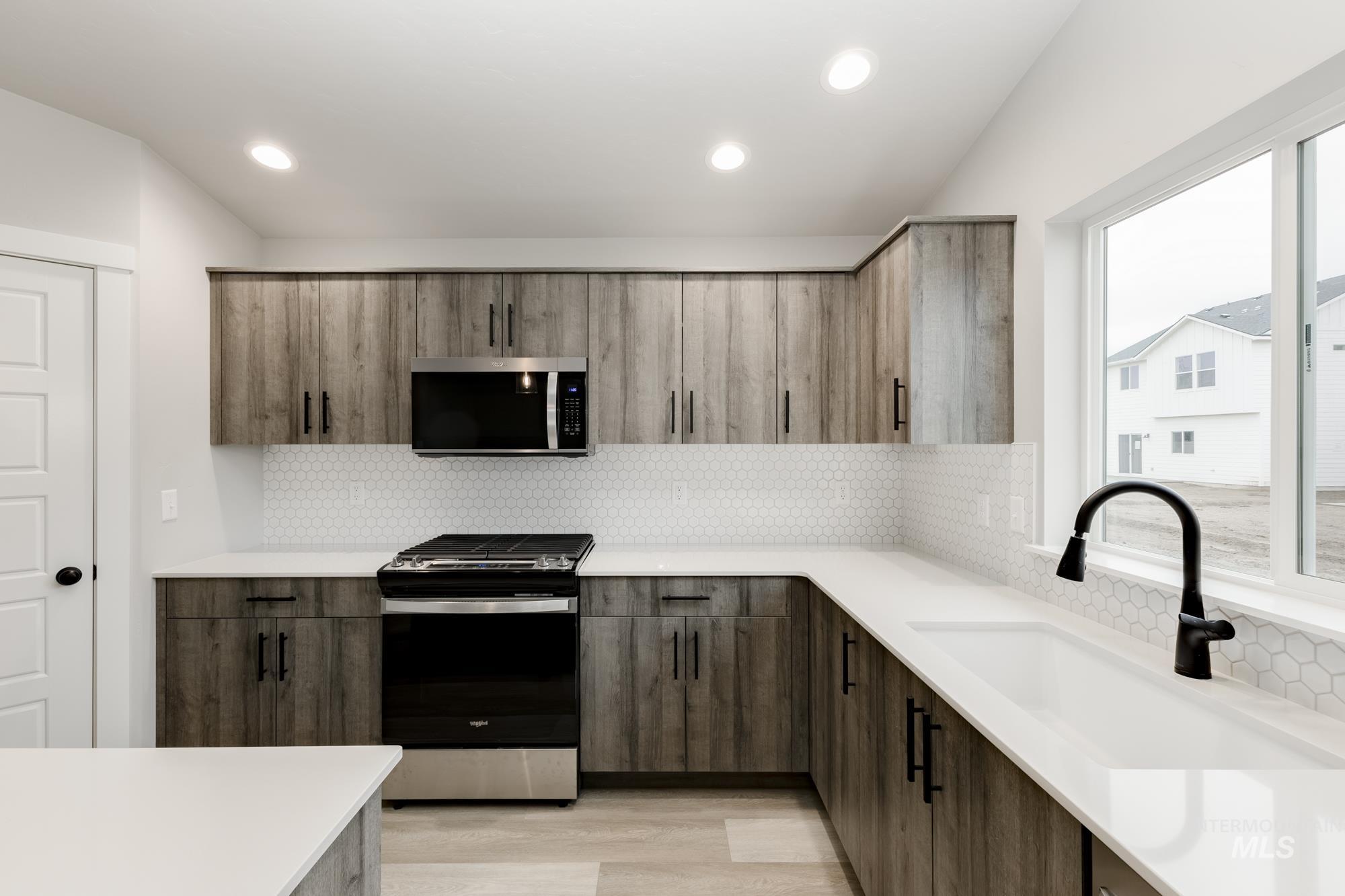 Kitchen featuring stainless steel appliances, decorative backsplash, light wood finished floors, light stone countertops, and modern cabinets