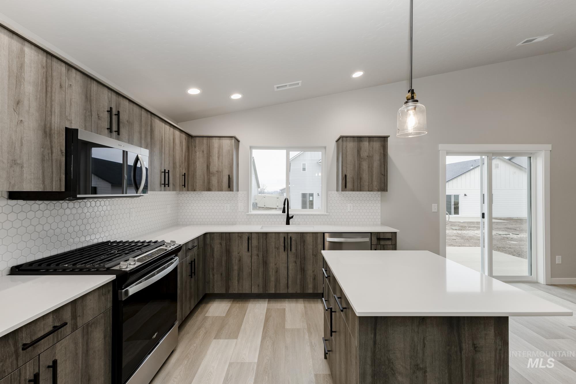 Kitchen with lofted ceiling, appliances with stainless steel finishes, tasteful backsplash, pendant lighting, and modern cabinets