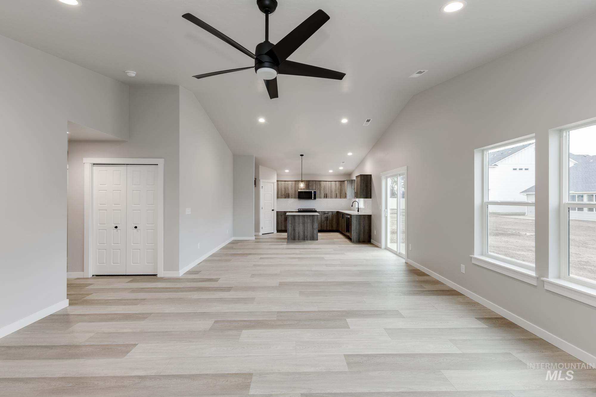 Unfurnished living room with vaulted ceiling, recessed lighting, light wood finished floors, and ceiling fan