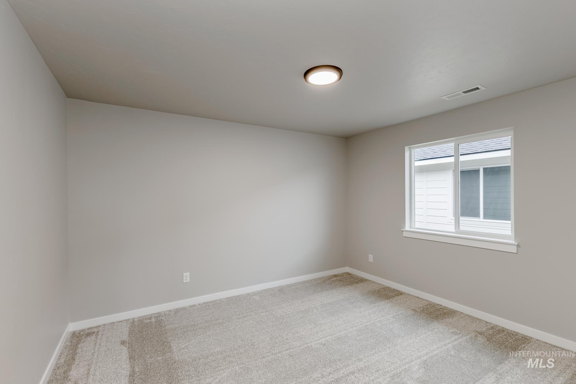 Empty room with light colored carpet and baseboards