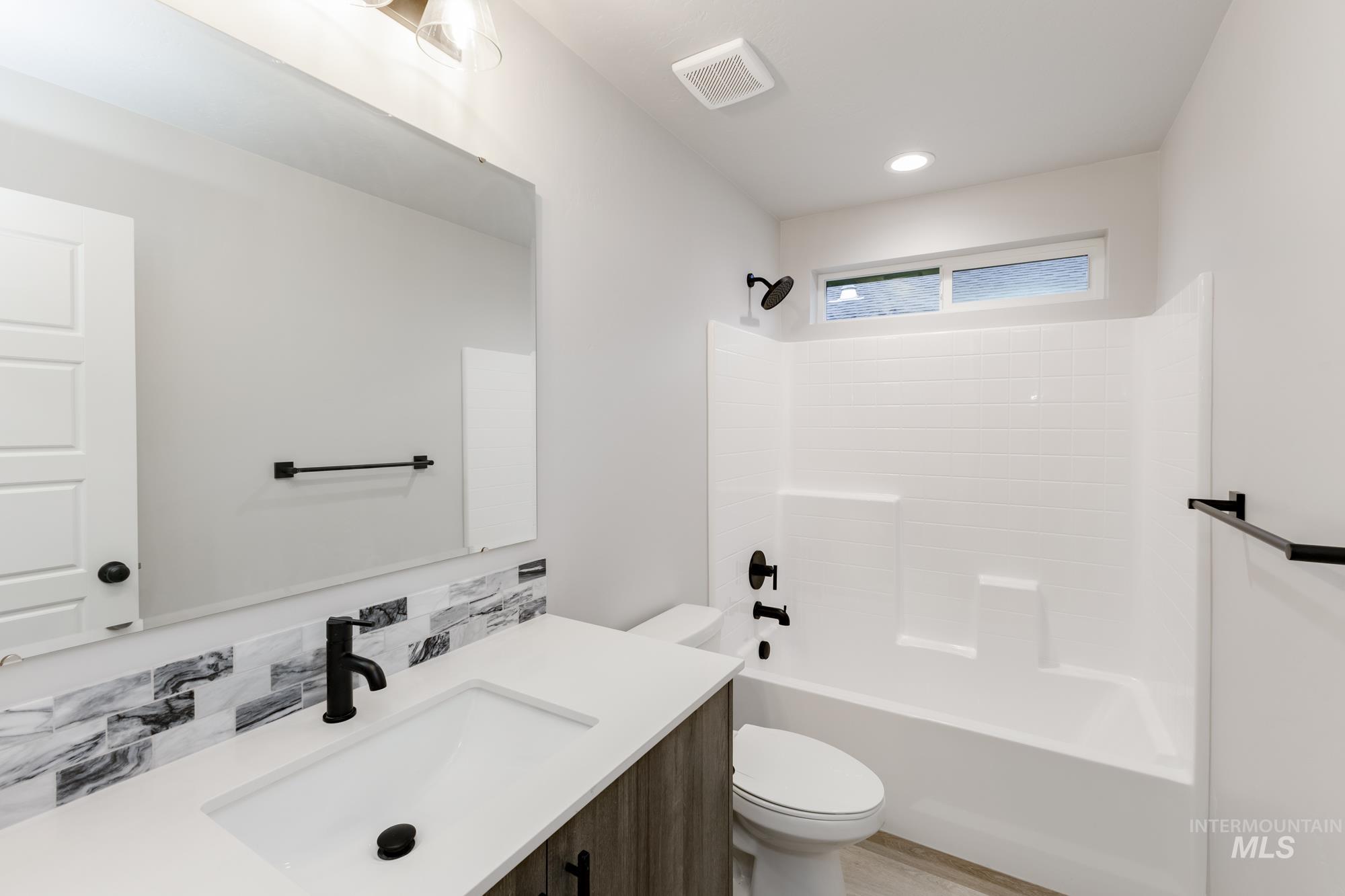Full bathroom with vanity, tub / shower combination, and tasteful backsplash
