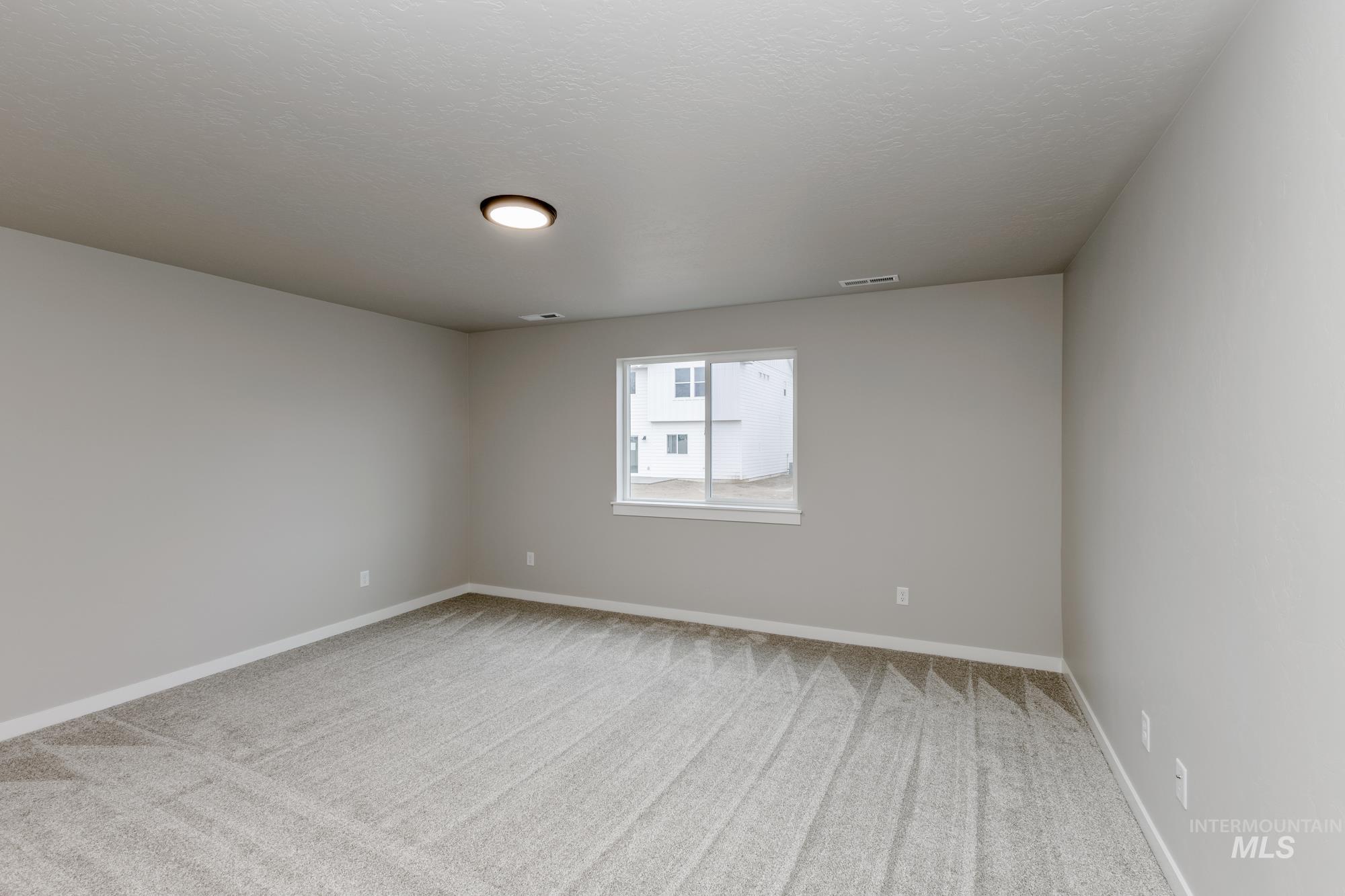 Spare room with light colored carpet and a textured ceiling