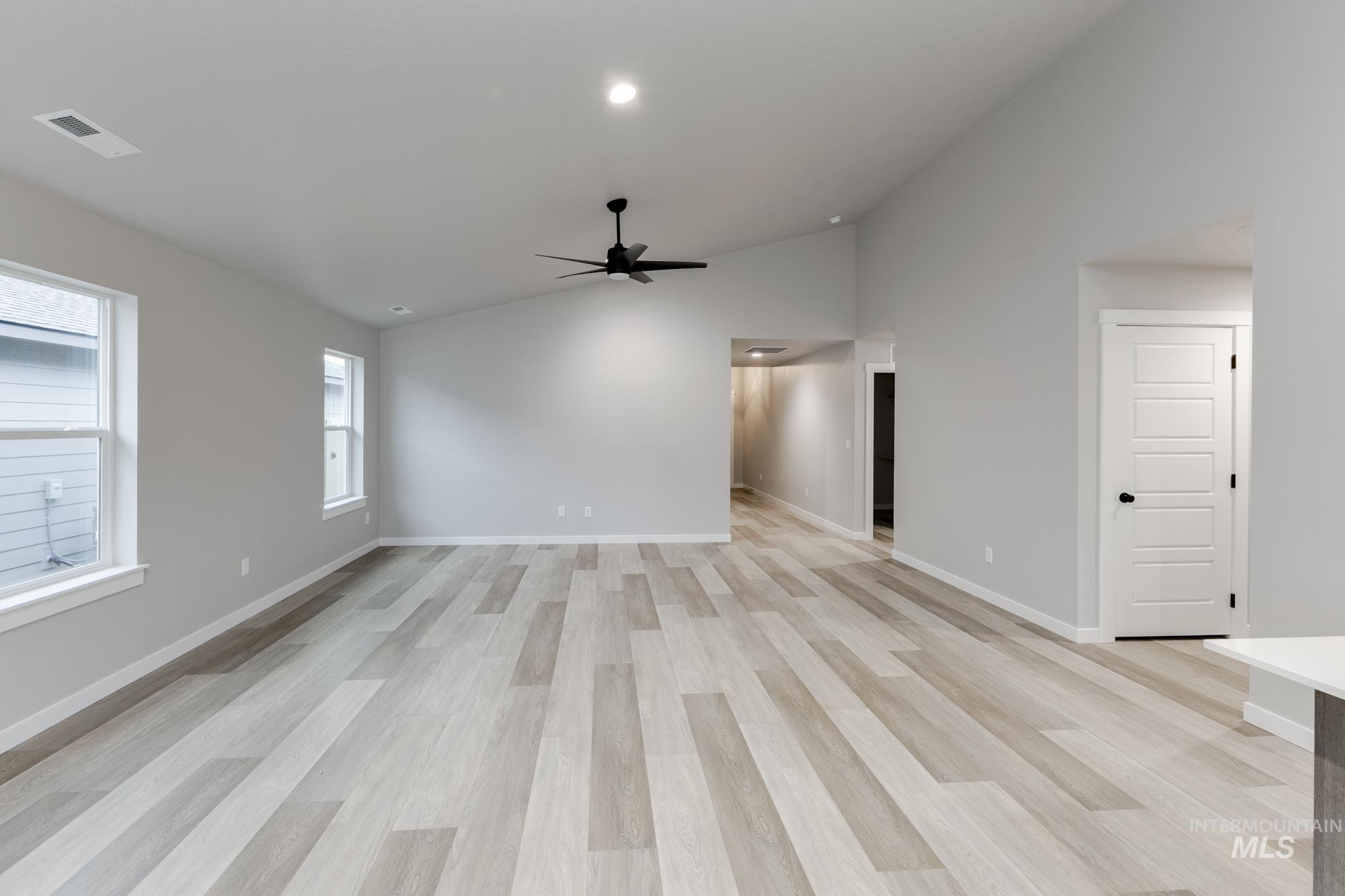 Empty room with lofted ceiling, light wood finished floors, and ceiling fan