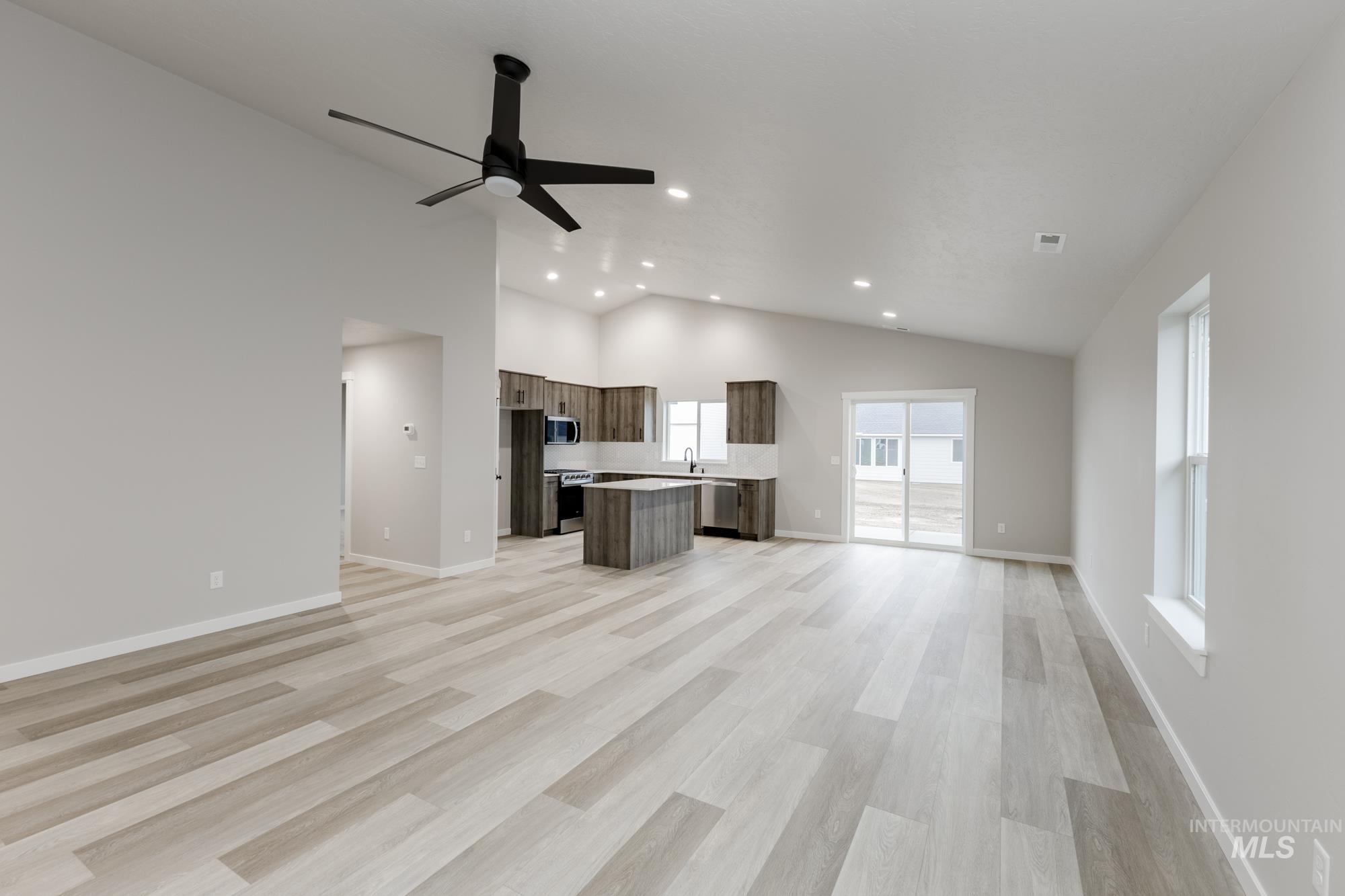 Unfurnished living room with vaulted ceiling, light wood-type flooring, recessed lighting, and a ceiling fan