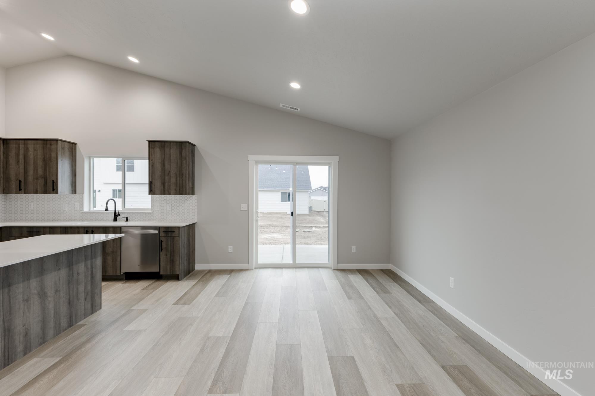 Kitchen with modern cabinets, backsplash, dark brown cabinets, plenty of natural light, and vaulted ceiling