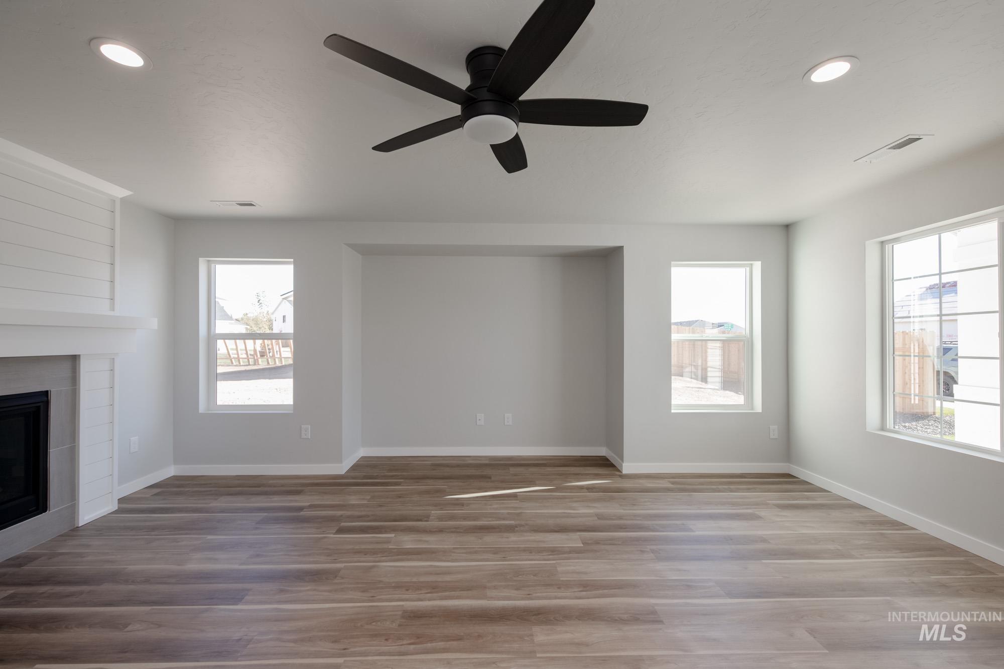 Unfurnished living room featuring recessed lighting, light wood-type flooring, a fireplace, ceiling fan, and plenty of natural light