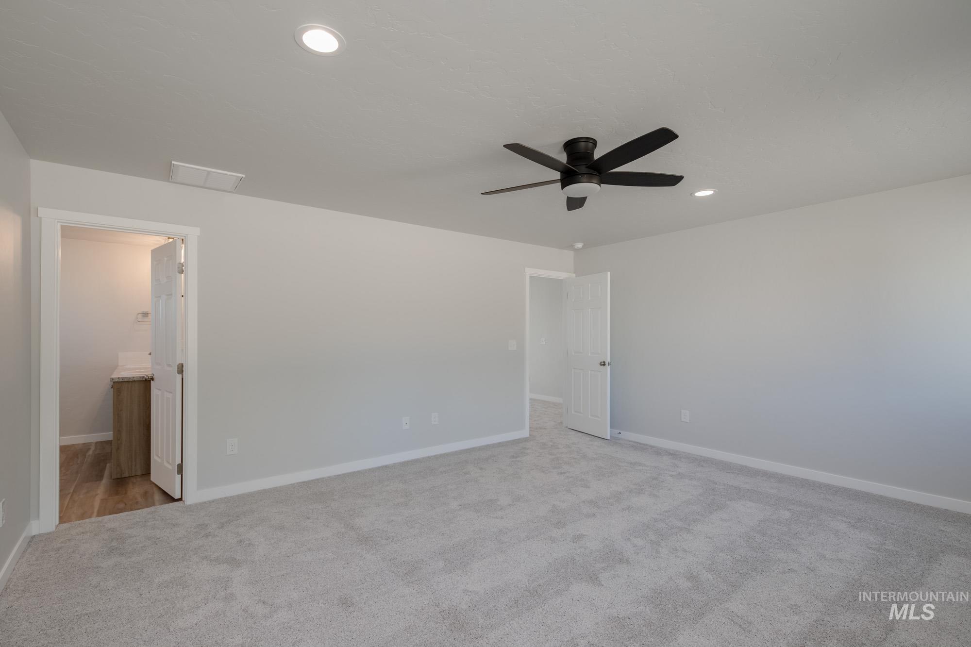 Unfurnished bedroom with light carpet, ensuite bath, a ceiling fan, and recessed lighting