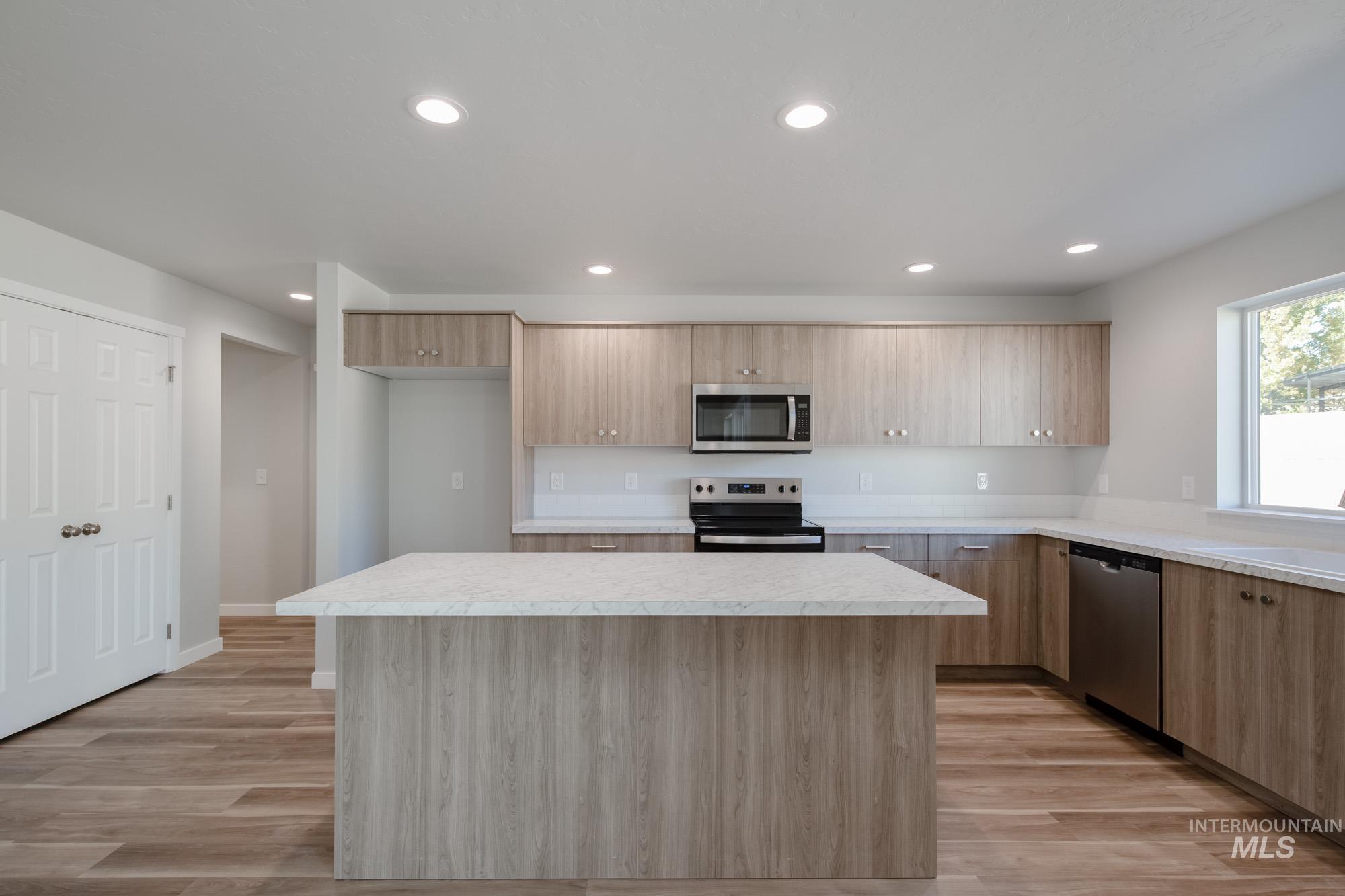 Kitchen with light countertops, a kitchen island, stainless steel appliances, recessed lighting, and light wood-style flooring