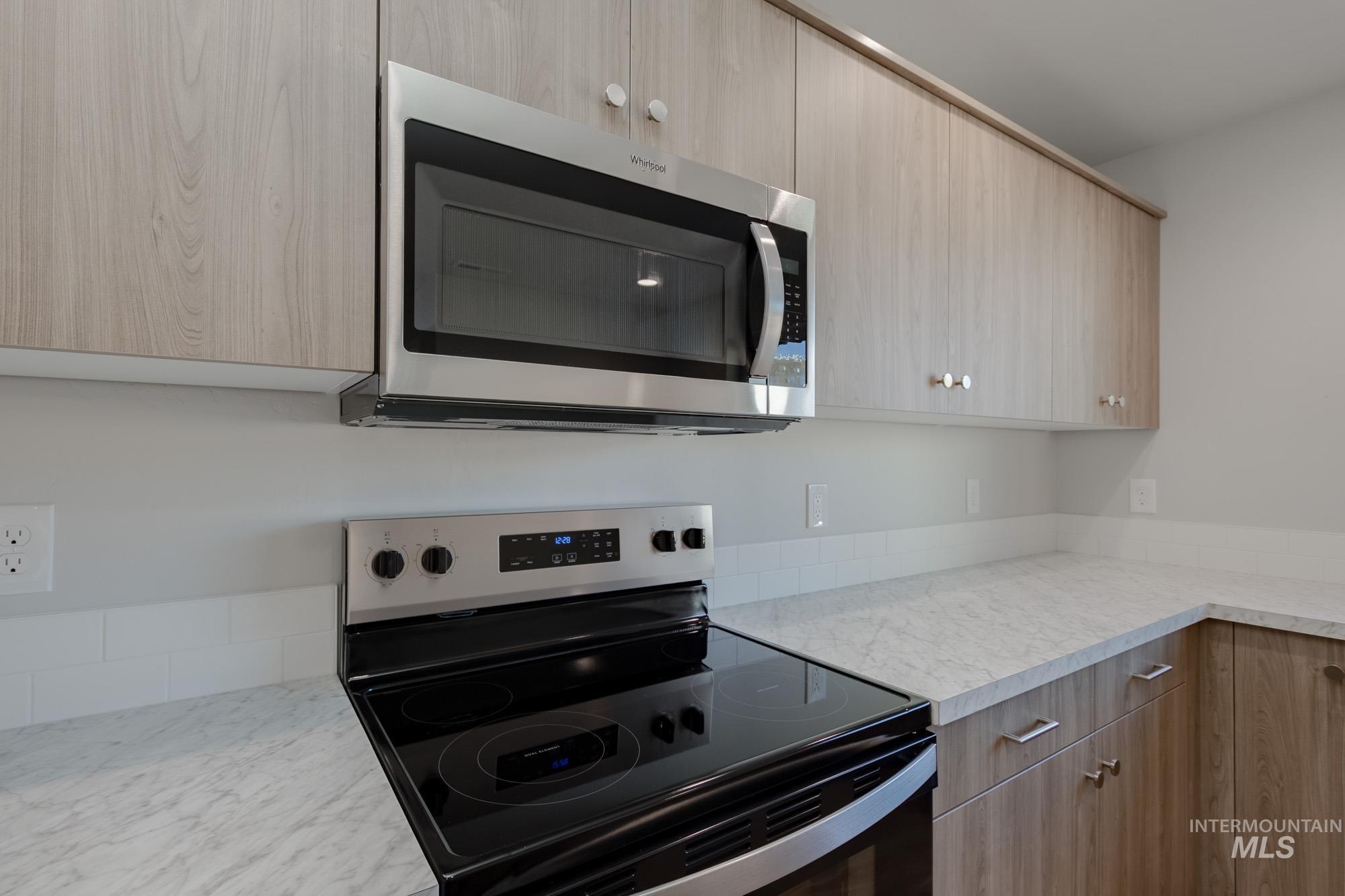 Kitchen with stainless steel appliances, modern cabinets, and light brown cabinets