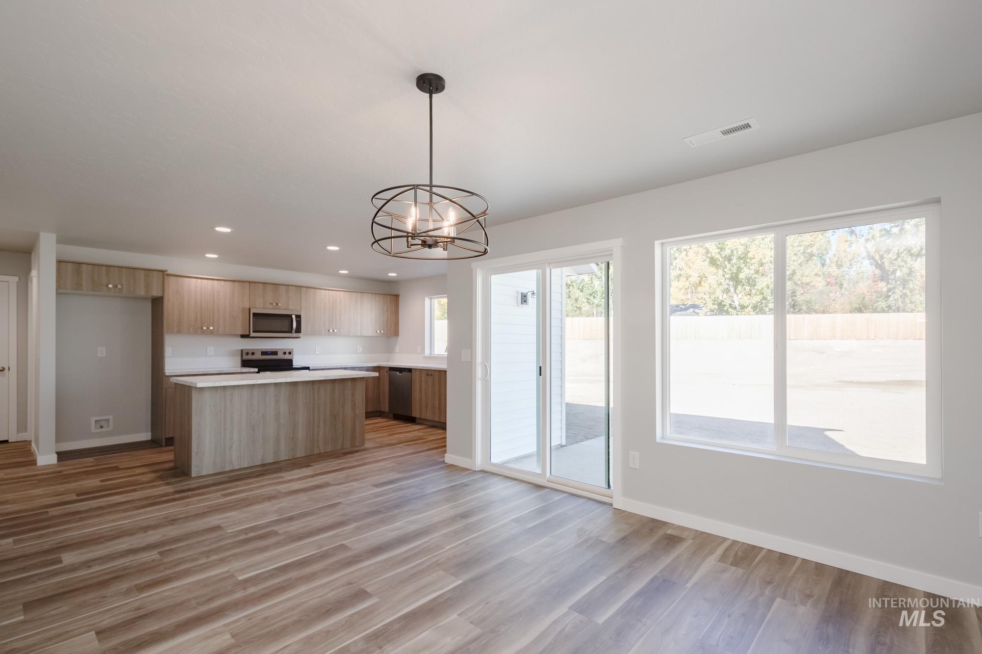 Kitchen with open floor plan, a chandelier, light countertops, pendant lighting, and a kitchen island